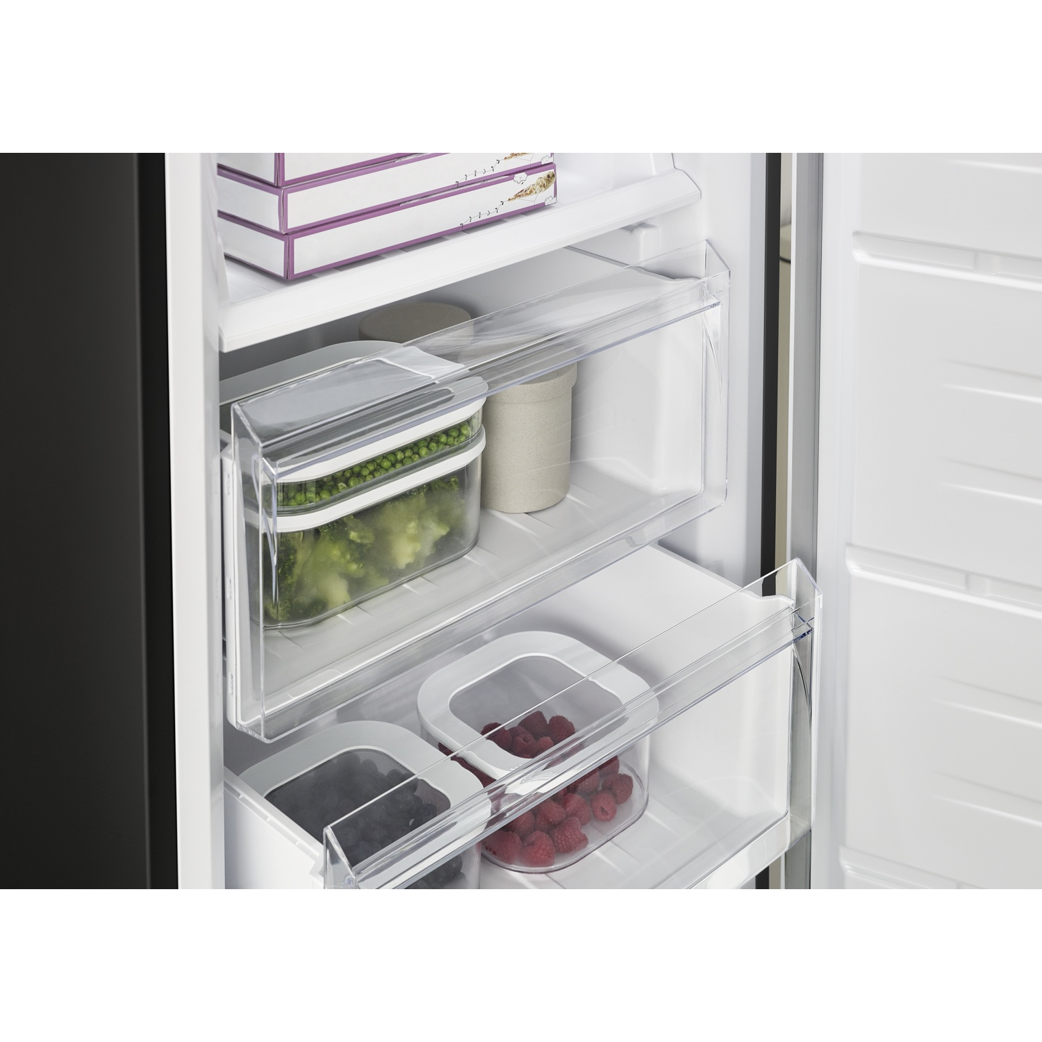 Freezer interior with food containers: peas, blueberries, and raspberries.