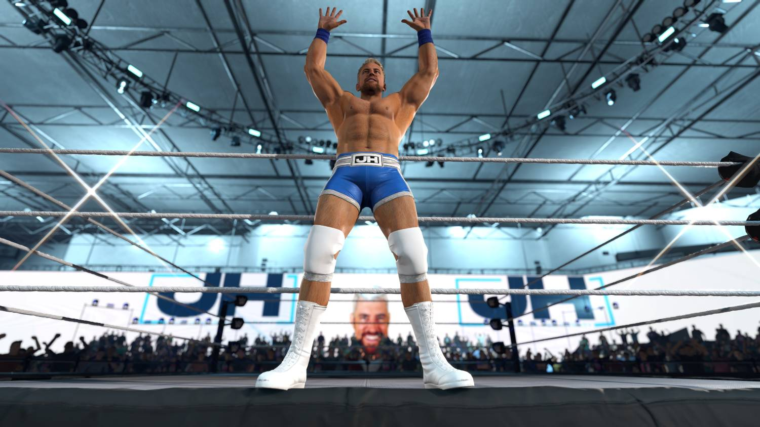 Un luchador con equipo azul levanta los brazos en victoria en un ring, público detrás.