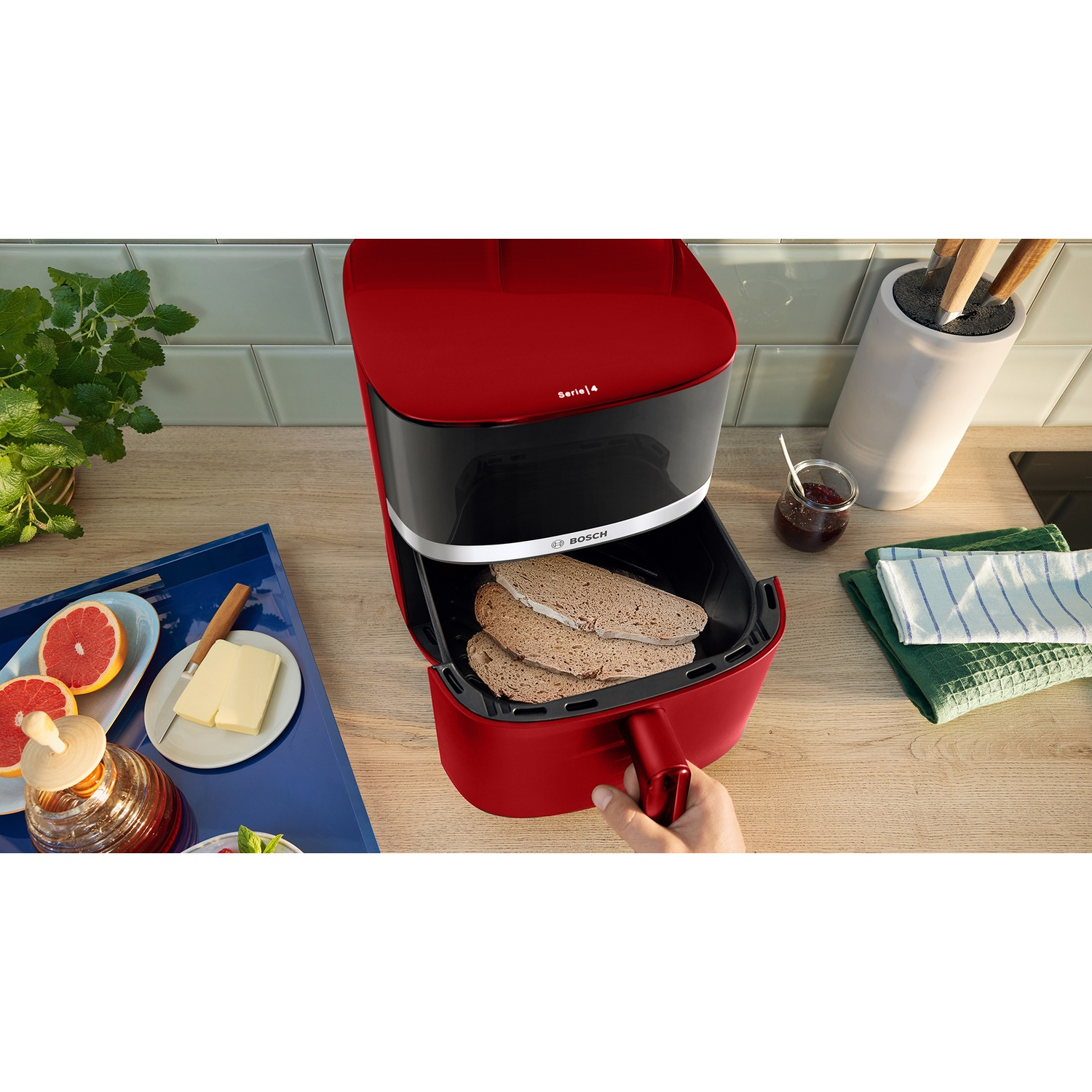 Friggitrice rossa Bosch con pane nel cestello su bancone legno.