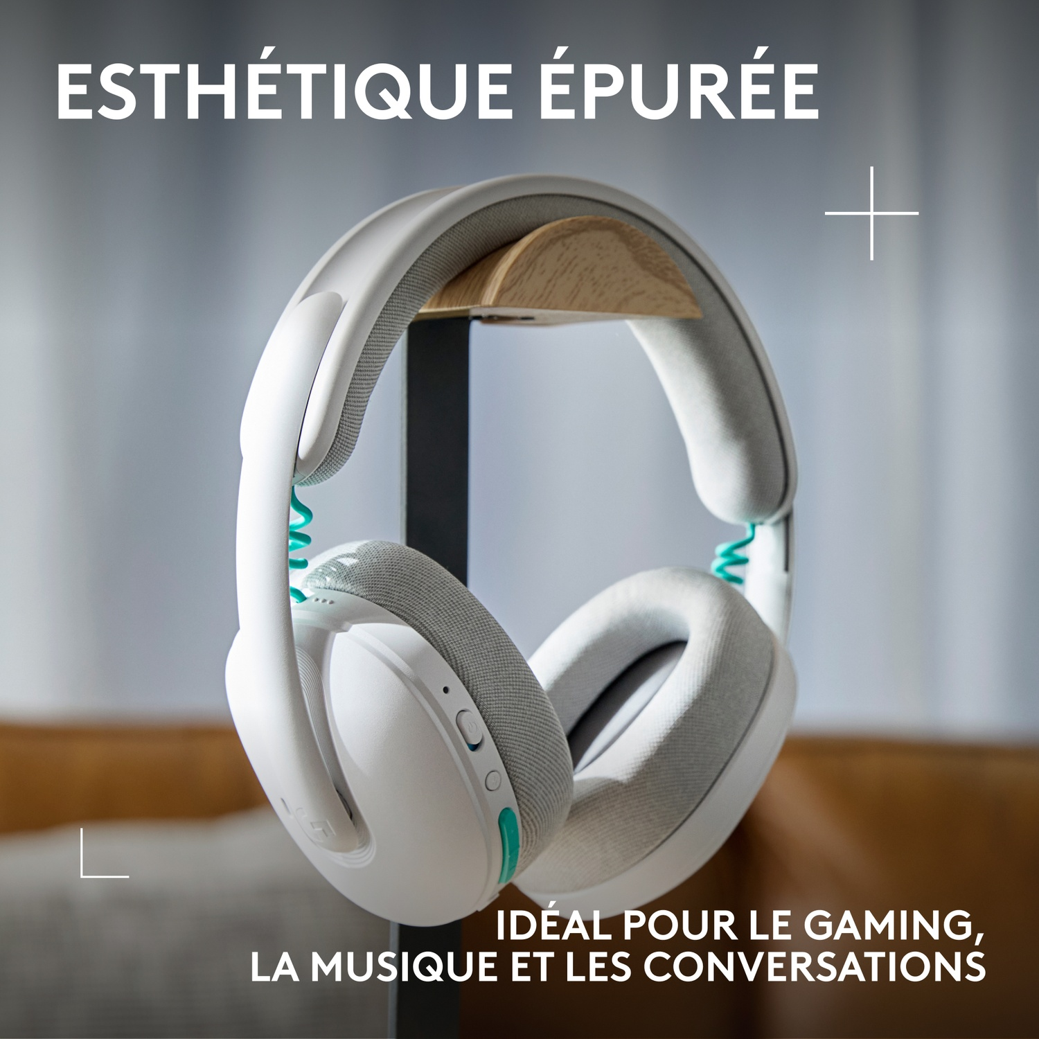 White headphones with grey earcups, hanging from a wooden stand.