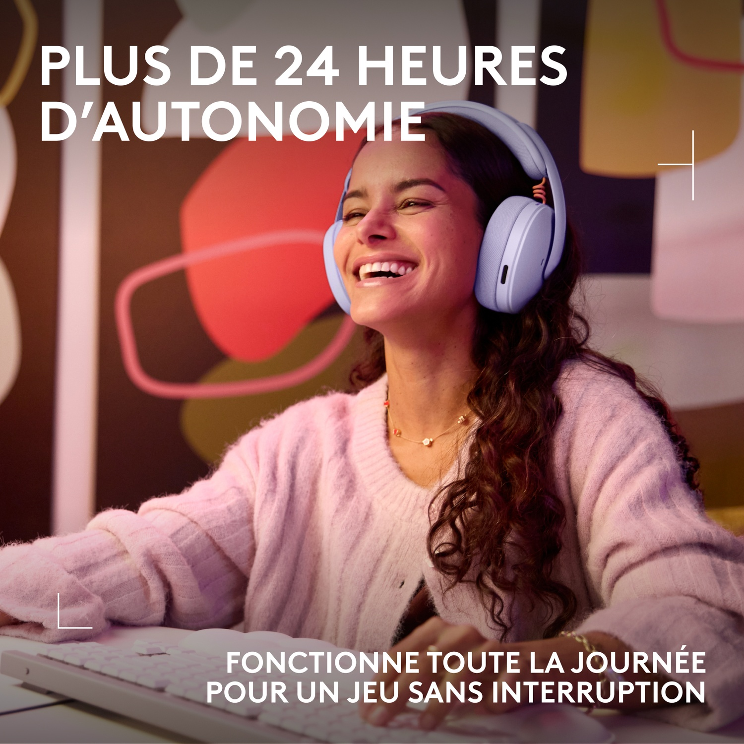 A smiling woman wearing headphones sits at a computer, typing.