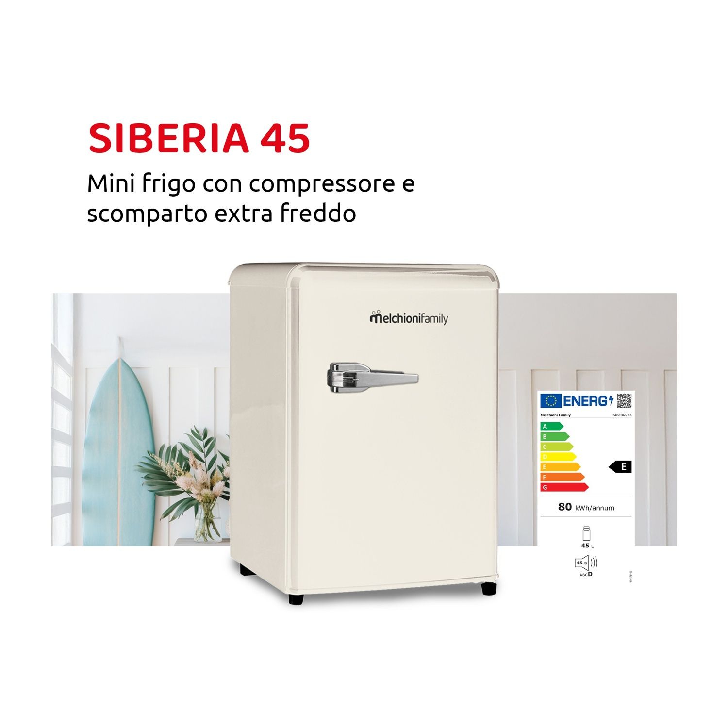 Un minifrigo color crema con maniglia argentata vicino a una tavola da surf e fiori.