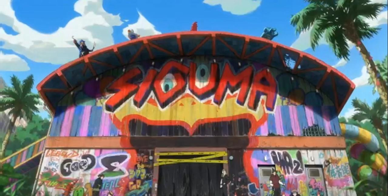 Buntes Gebäude mit Graffiti und Palmen unter blauem Himmel.