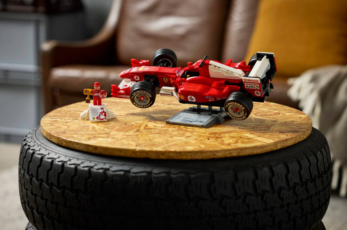 Ein rotes Lego-Formel-1-Auto mit einem Fahrer-Minifiguren auf einem Holztisch.