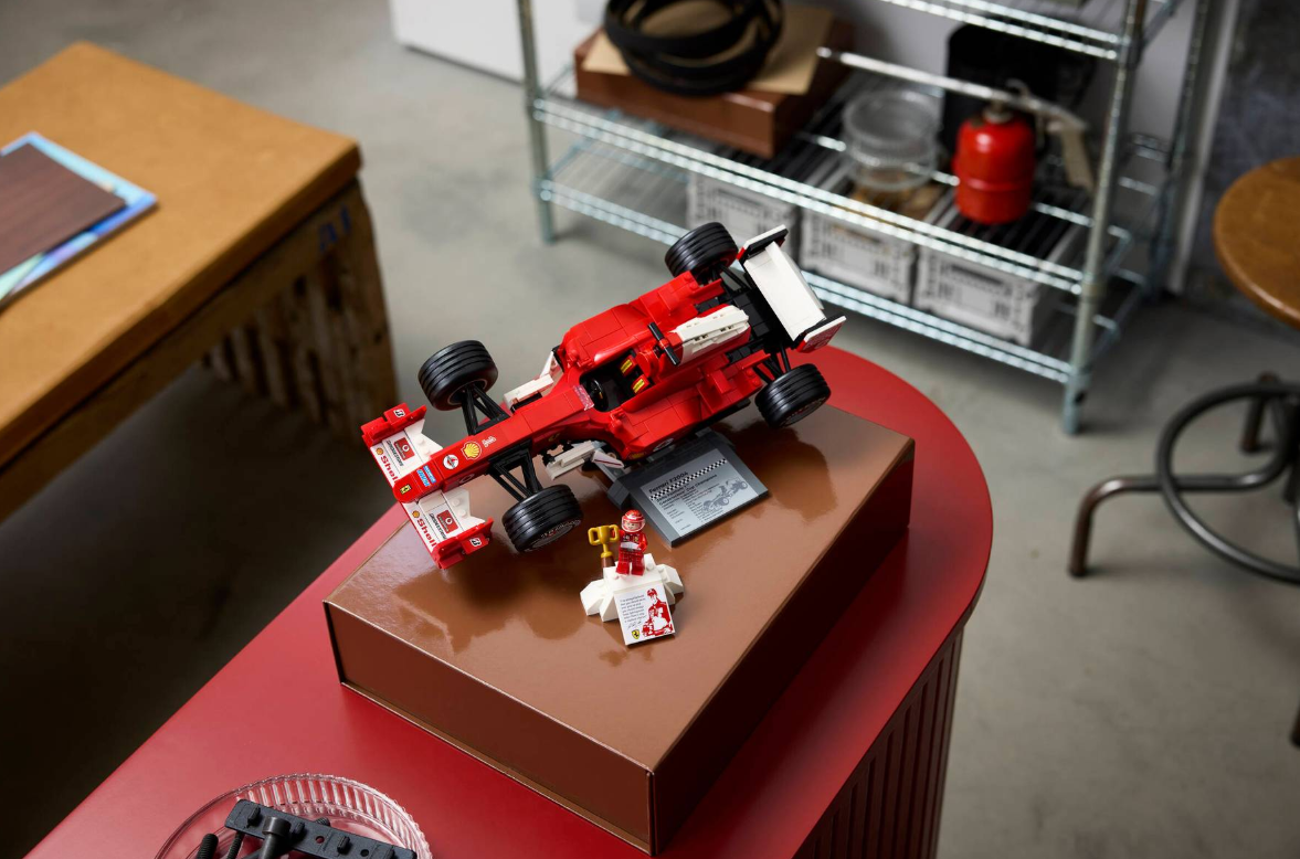 Ein rotes Lego-Formel-1-Auto mit Fahrer und Podest auf einem braunen Kasten.