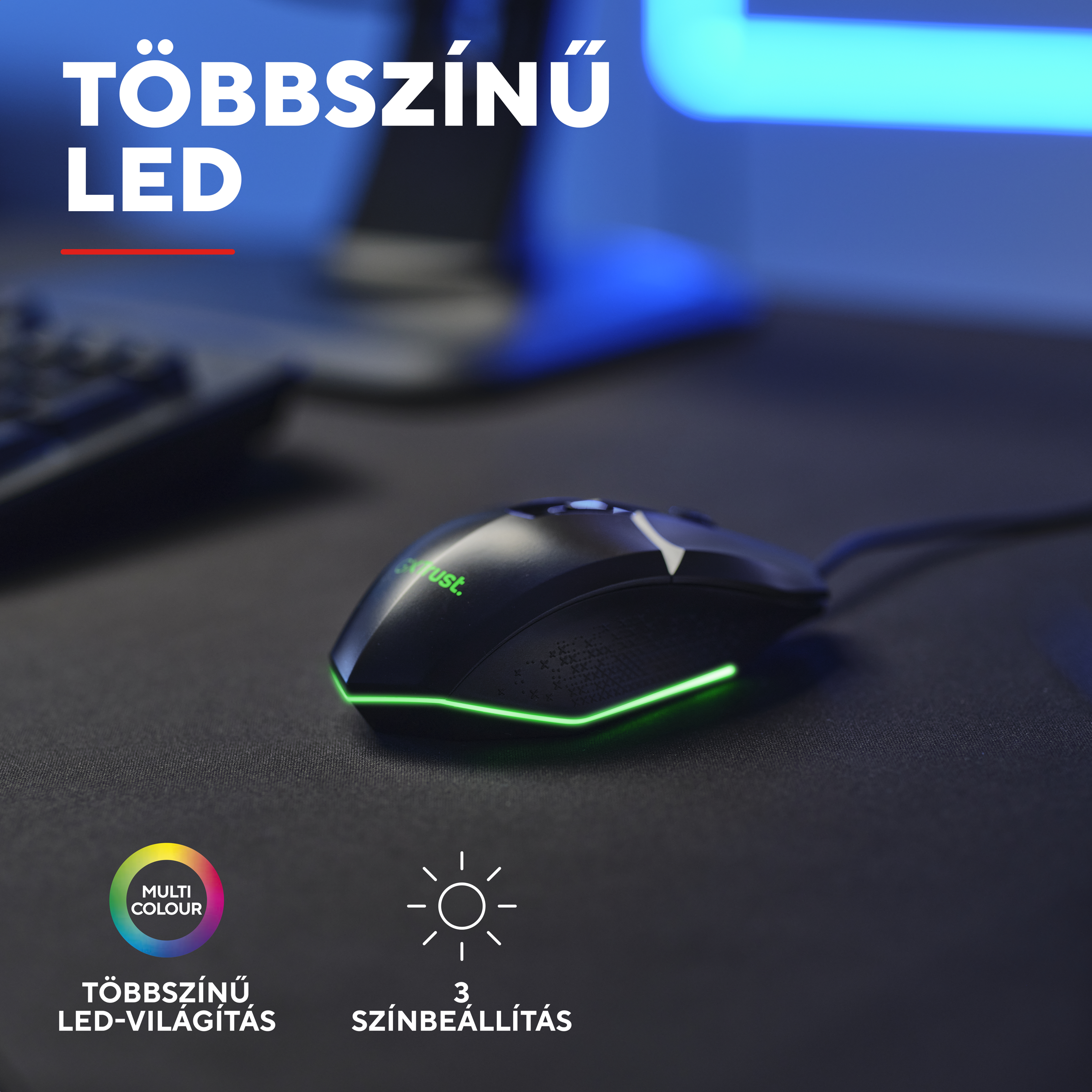 Fekete gamer egér zöld LED világítással és logóval asztalon.