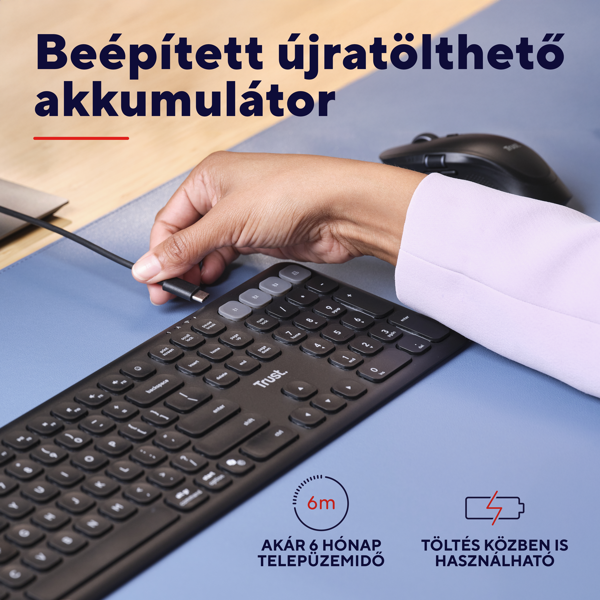 Egy kéz USB-C kábelt csatlakoztat egy egér melletti billentyűzethez.