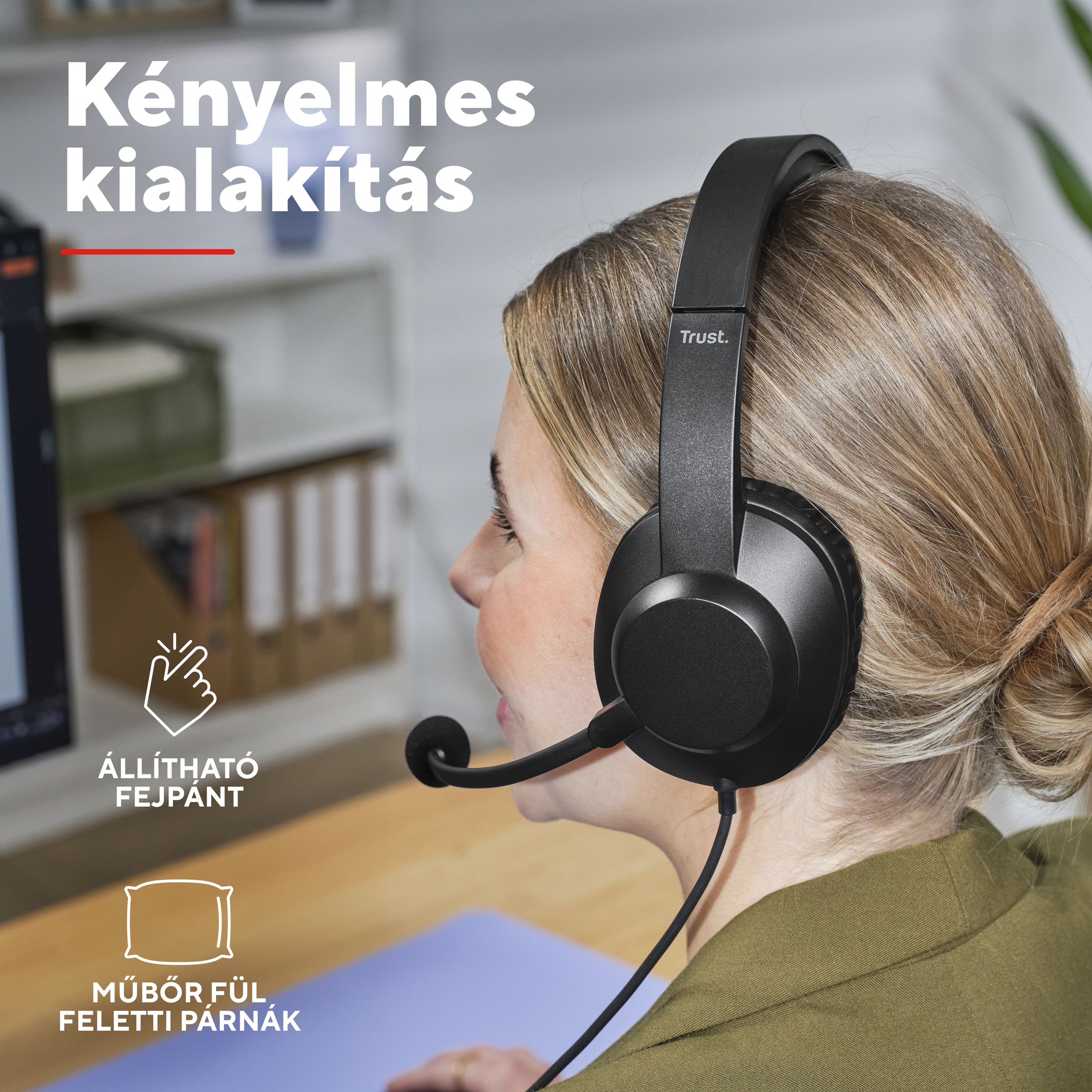 Egy nő fejhallgatóval és mikrofonnal az íróasztalánál ül.