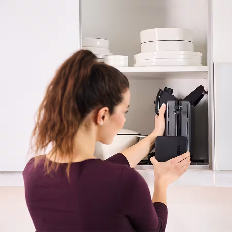 Kobieta wyjmuje czarny toster z szafki kuchennej.