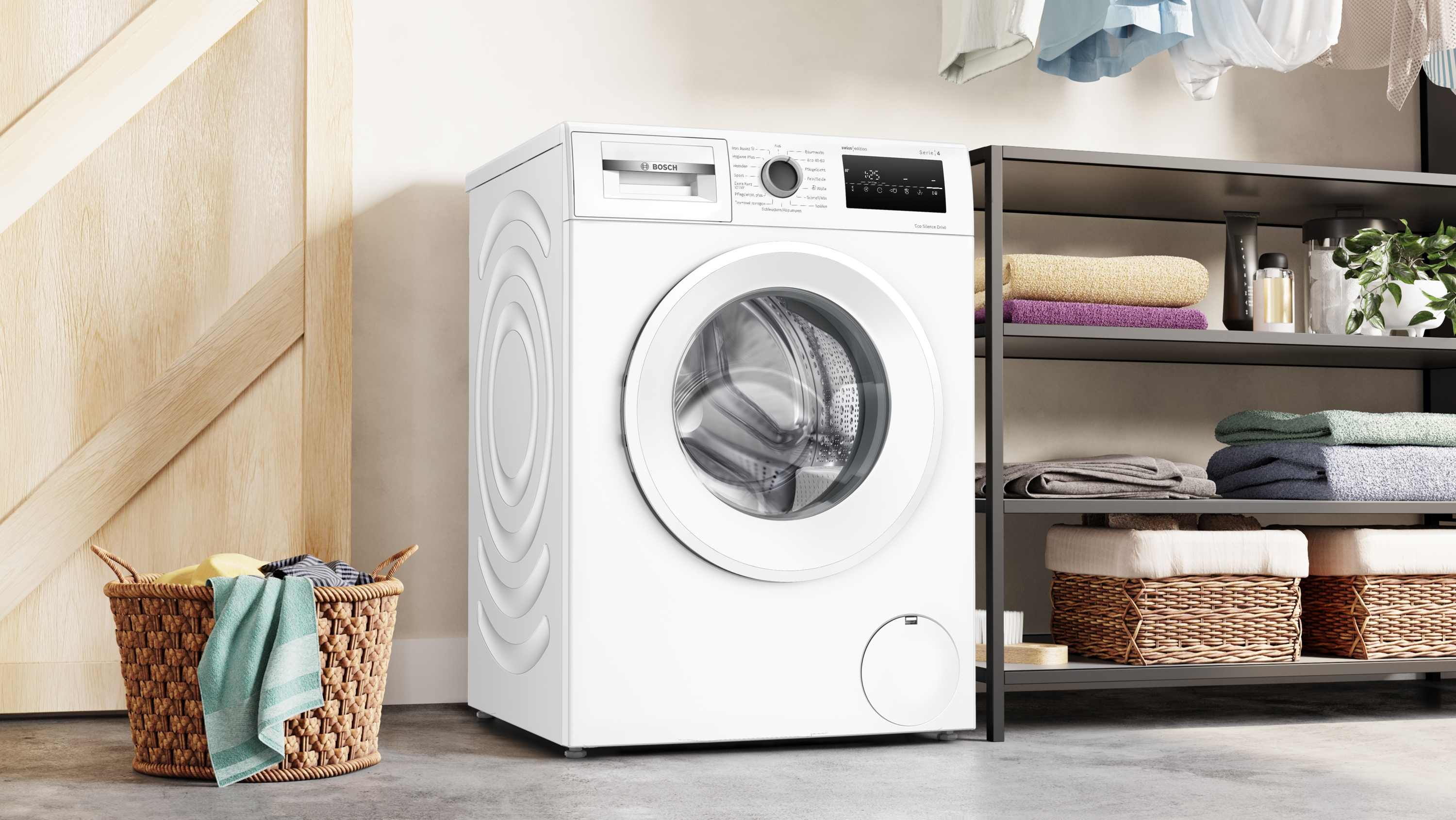 Eine weiße Bosch-Waschmaschine steht neben einem Wäschekorb und einem Regal mit Handtüchern.