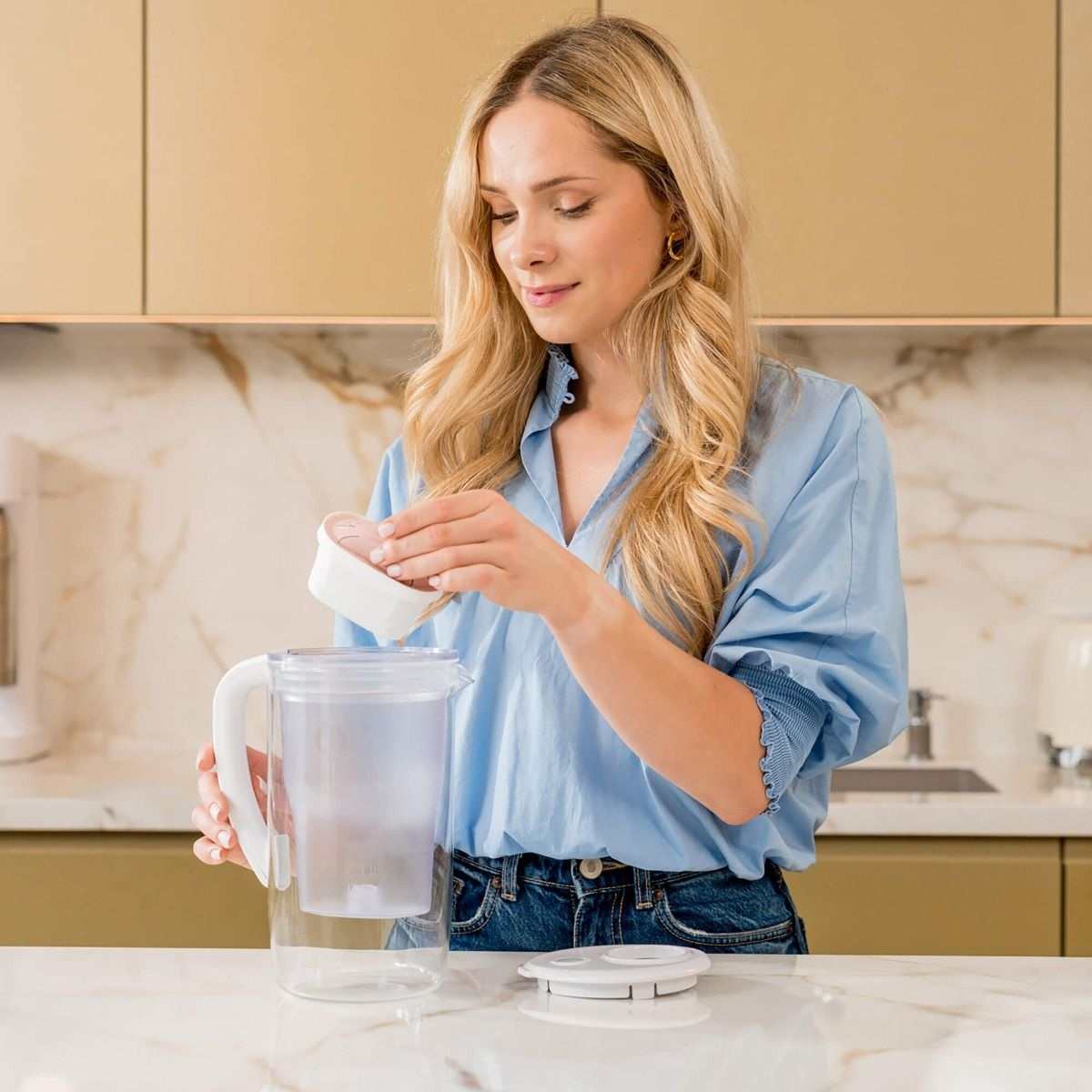 Kobieta wkłada filtr do dzbanka filtrującego wodę w kuchni.