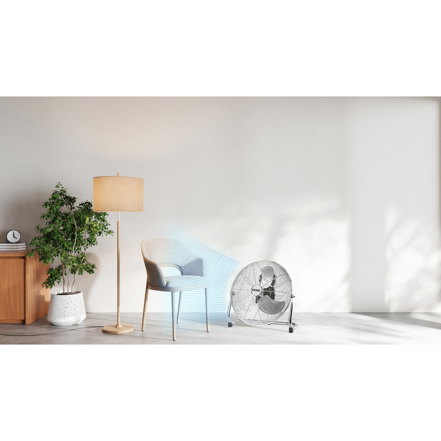 Un ventilatore in metallo fa circolare l'aria verso una sedia in una stanza minimalista con pianta.