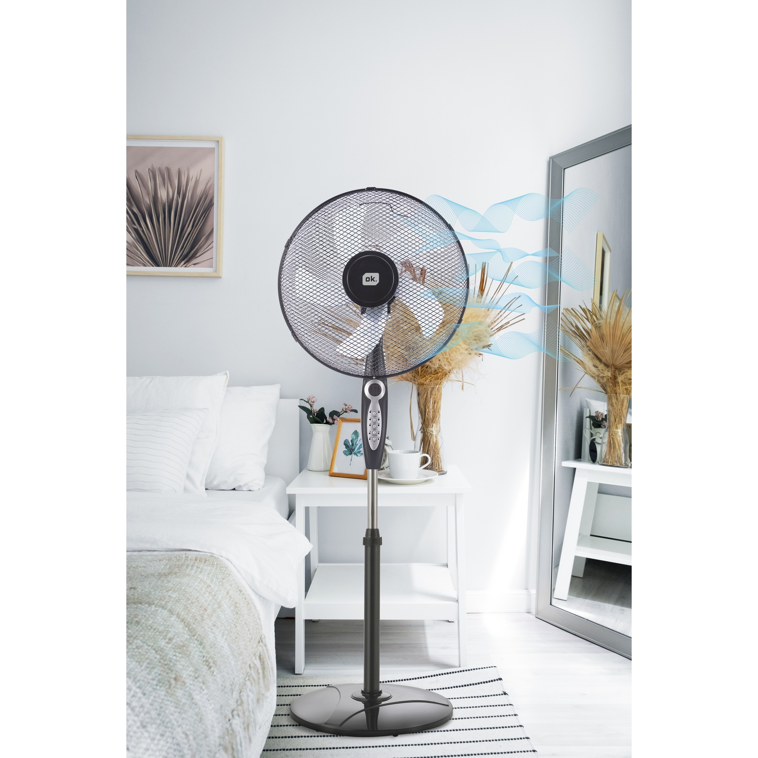 Un ventilatore da terra nero in una camera da letto, che soffia aria.