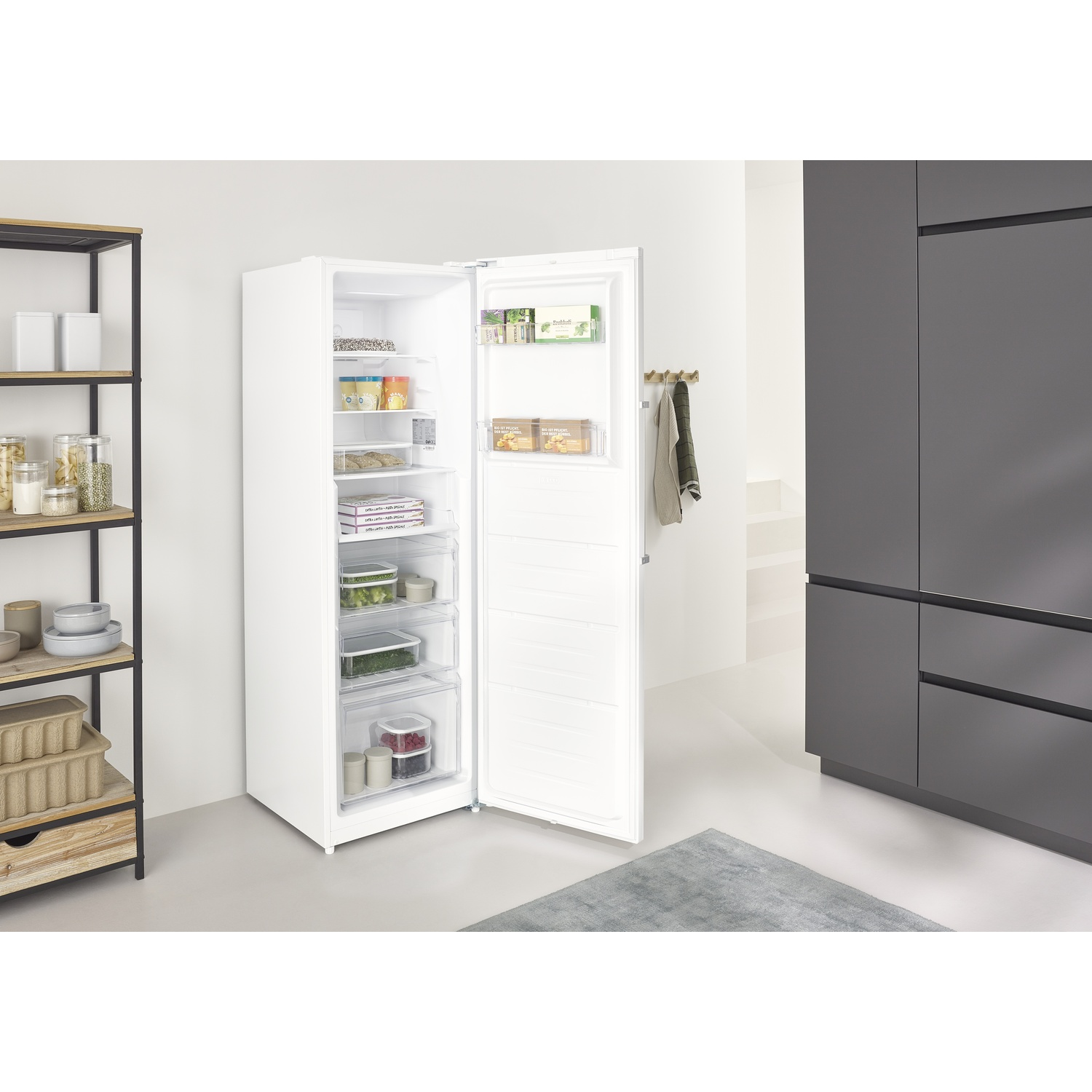 Un frigorifero bianco con porta aperta, pieno di cibo.