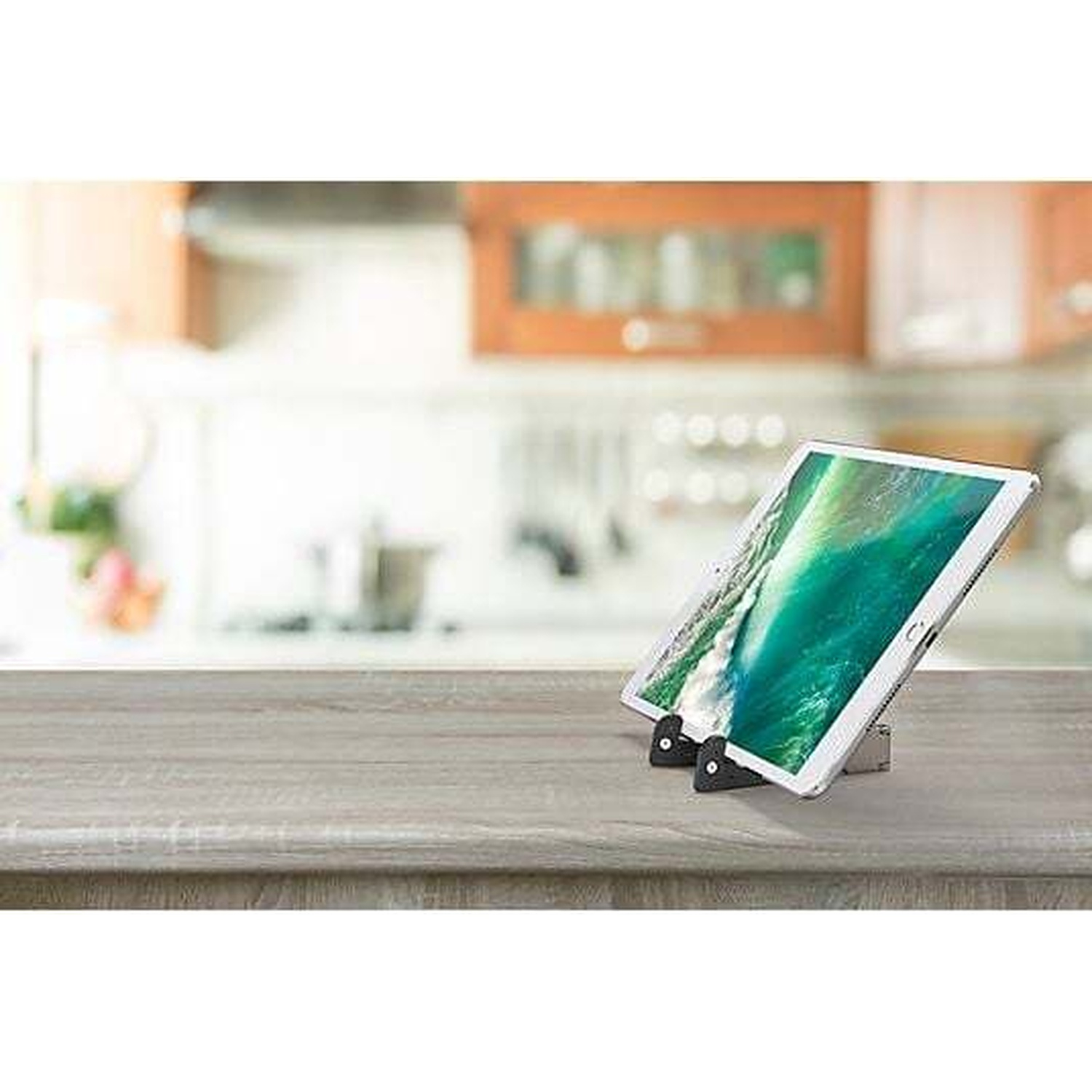 Une tablette à écran vert est sur un support sur une table en bois.