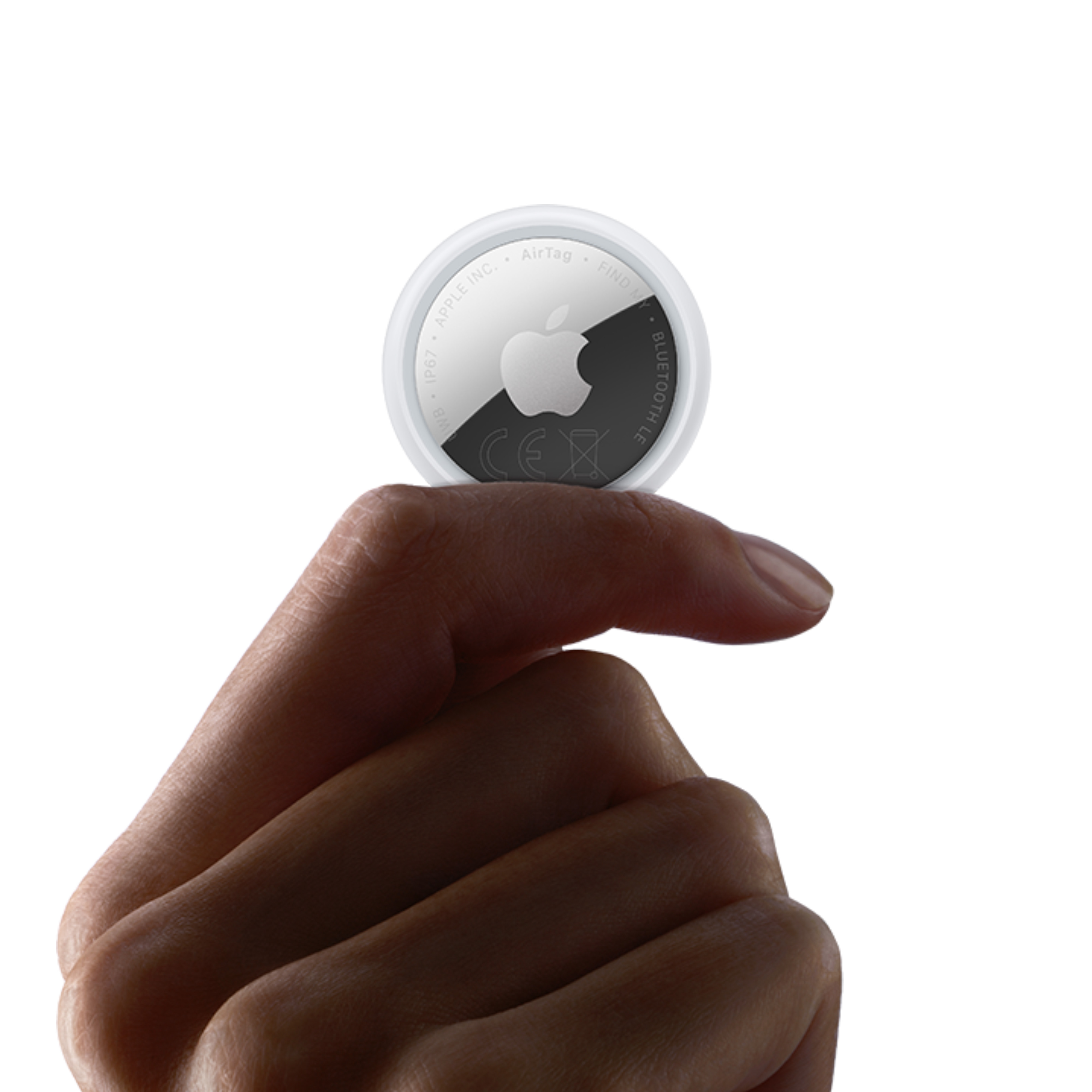Una mano tiene un AirTag Apple bianco con il logo Apple.
