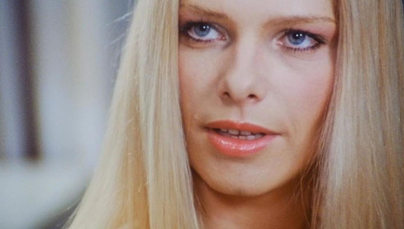 Nahaufnahme einer Frau mit blonden Haaren und blauen Augen, die auf der Seite schaut.