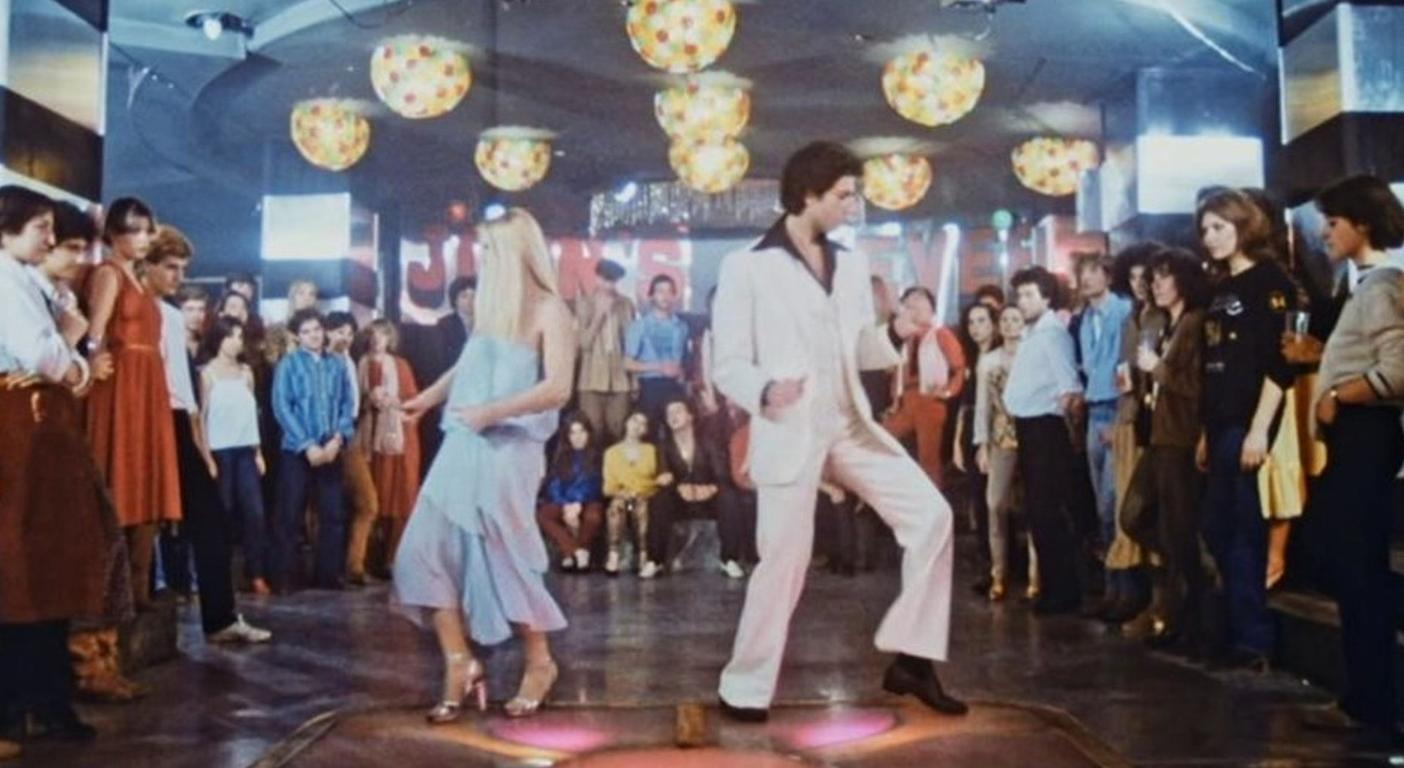 Tanzende Menschen in einem Nachtclub mit Discokugeln an der Decke.