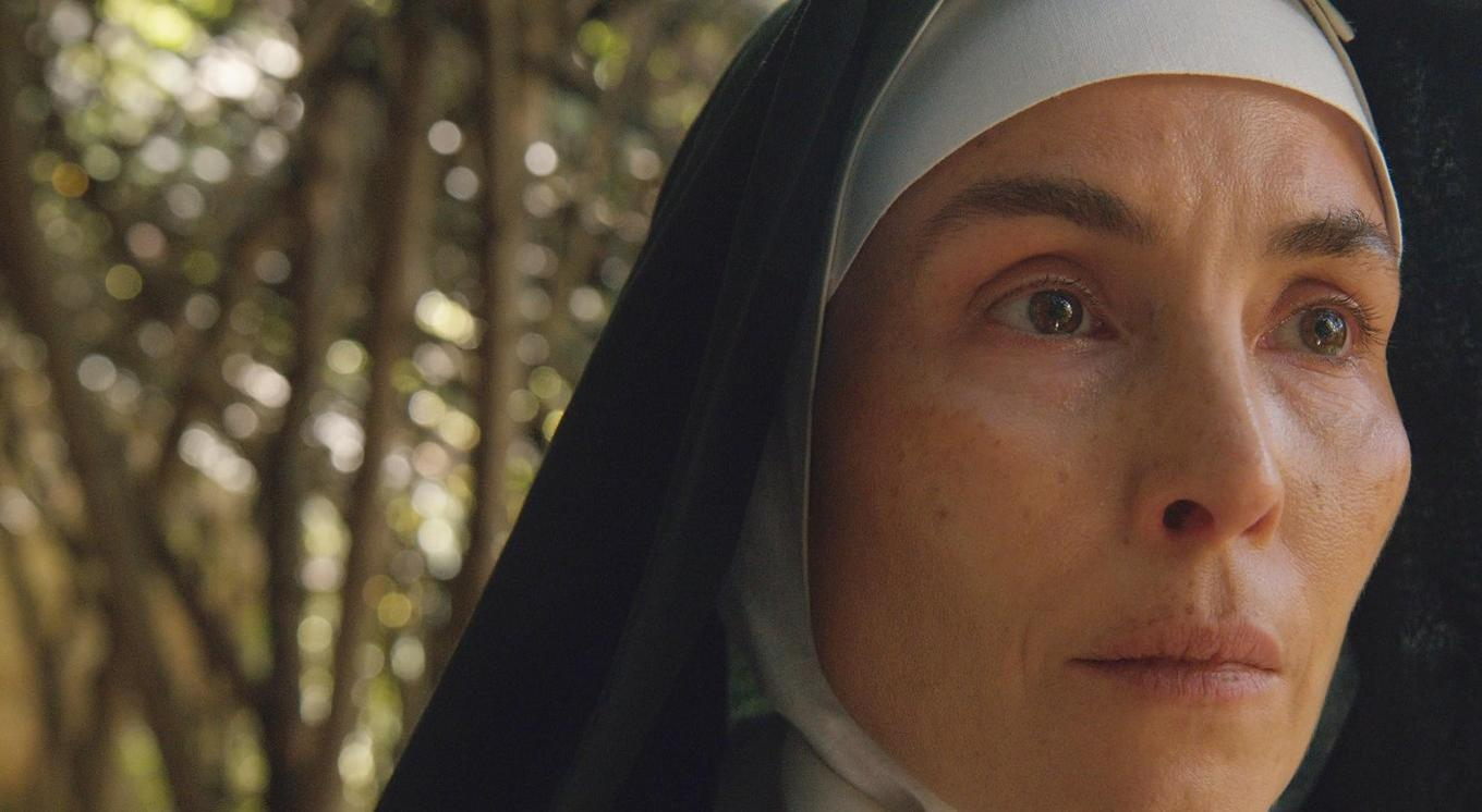 Nahaufnahme einer Nonne im Habit, mit verschwommenem grünen Hintergrund.