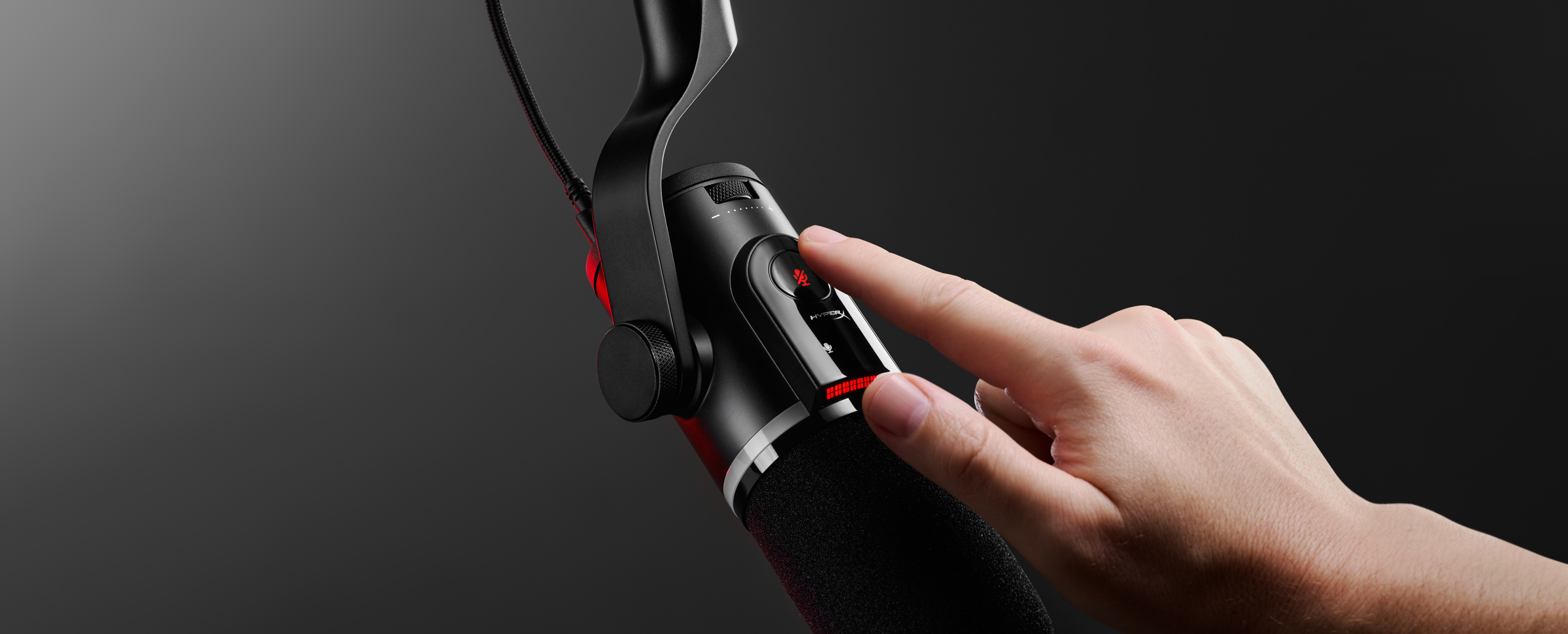 Una mano preme il pulsante di disattivazione audio su un microfono nero con indicatori LED rossi.