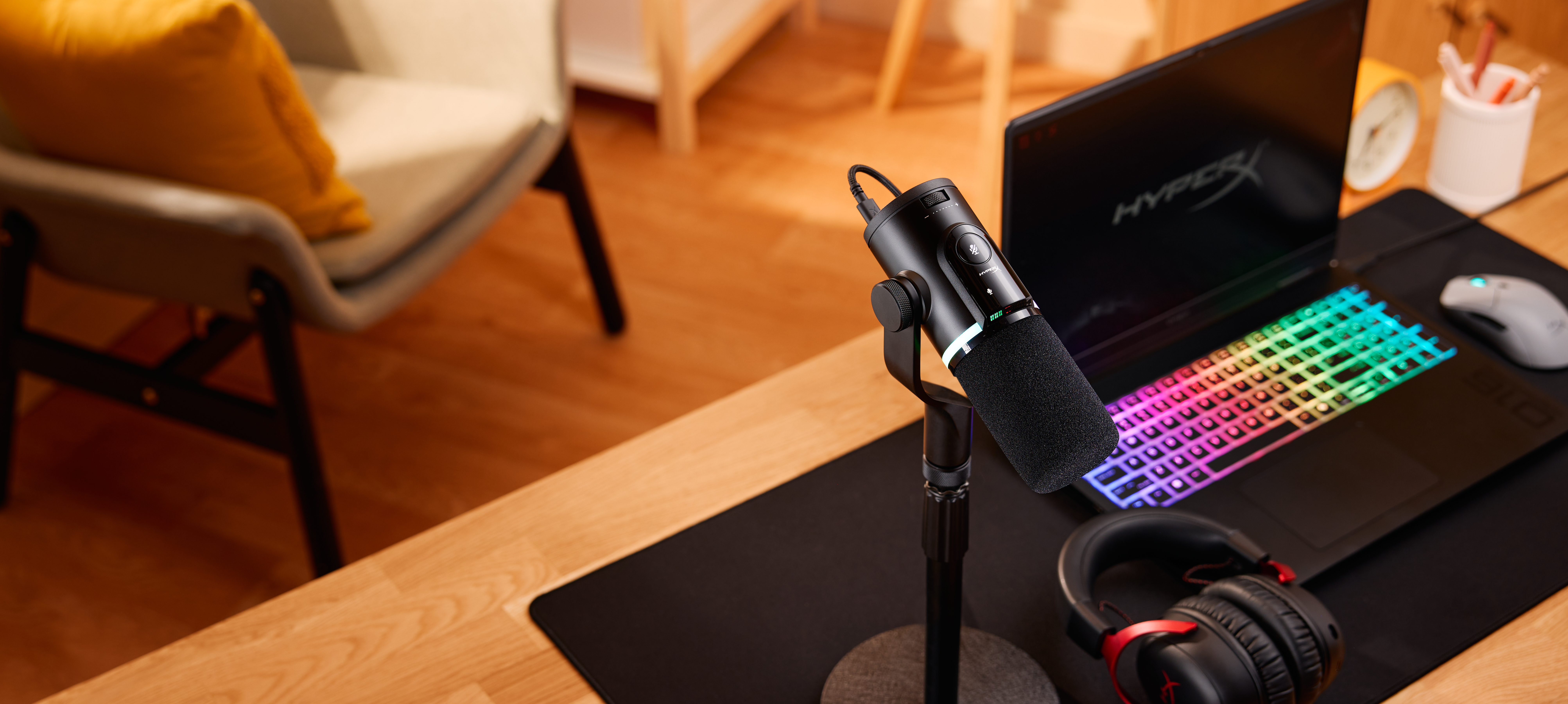 Un microfono nero accanto a un laptop con tastiera colorata.