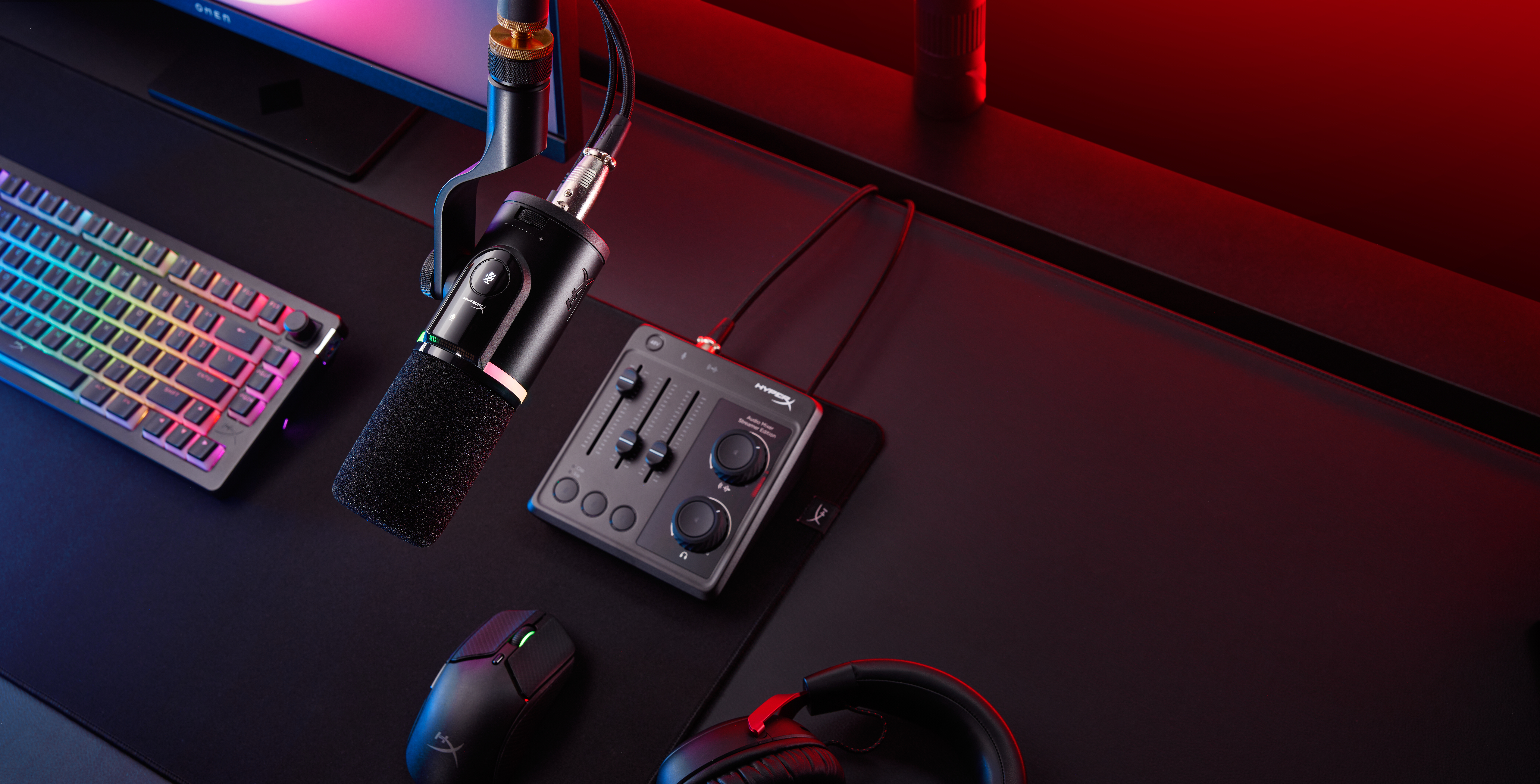 Una postazione da gioco con tastiera, mouse, microfono, mixer e cuffie.