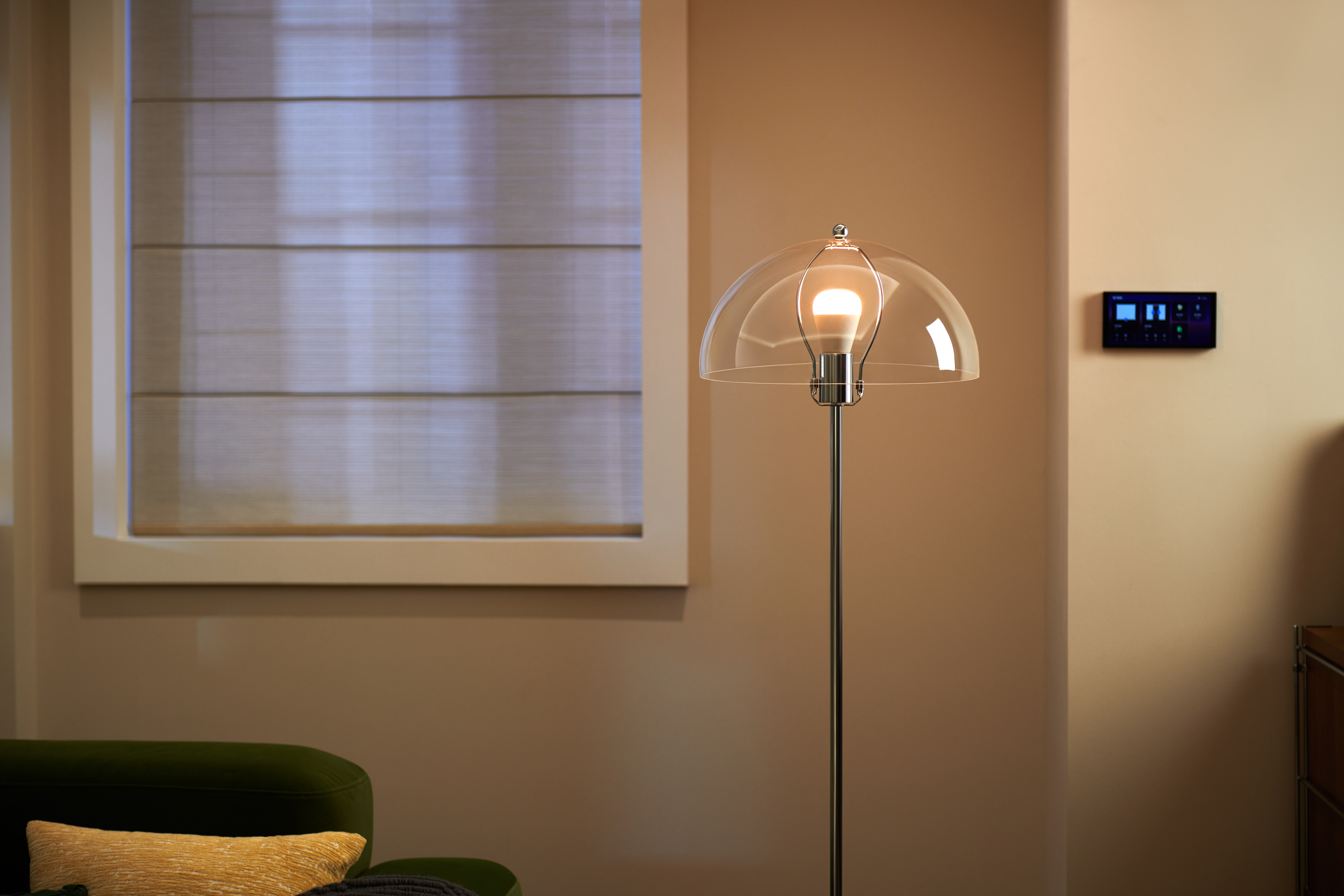 Ein moderner Stehlampe mit Glasglocke beleuchtet einen Raum mit Jalousien und Wandsteuerung.