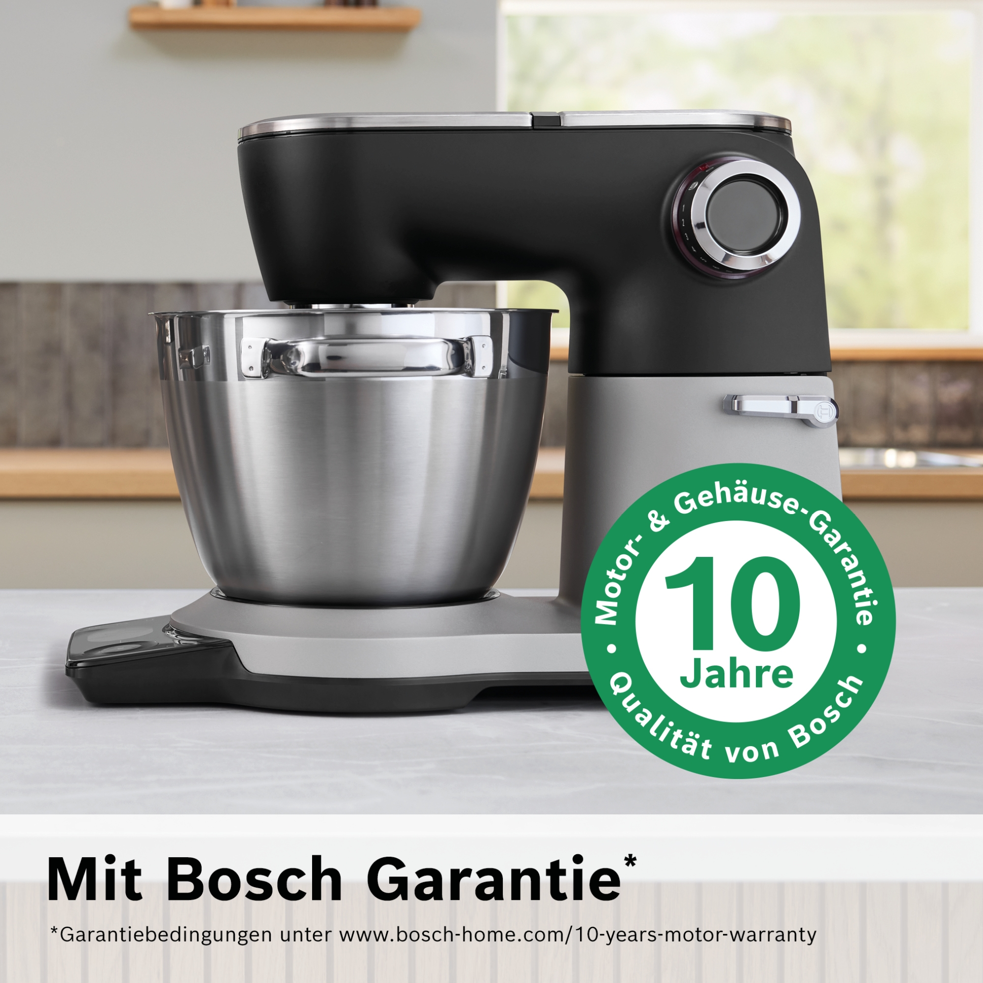 Ein schwarzer Küchenmixer mit Edelstahlschüssel und Garantie-Aufkleber.