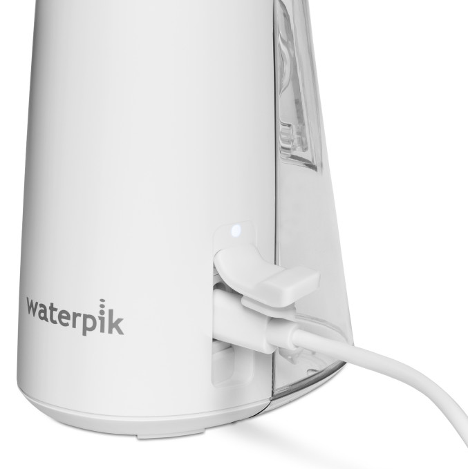 Biała podstawa irygatora Waterpik z podłączonym kablem ładującym.