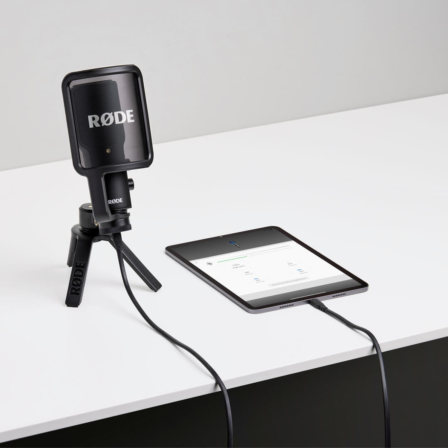 A RODE microphone on a tripod next to a tablet connected to it.