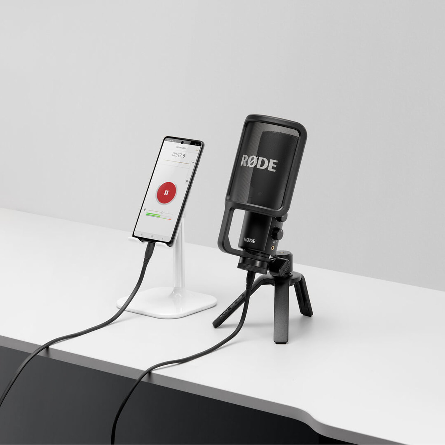Black microphone on stand next to smartphone with recording display.