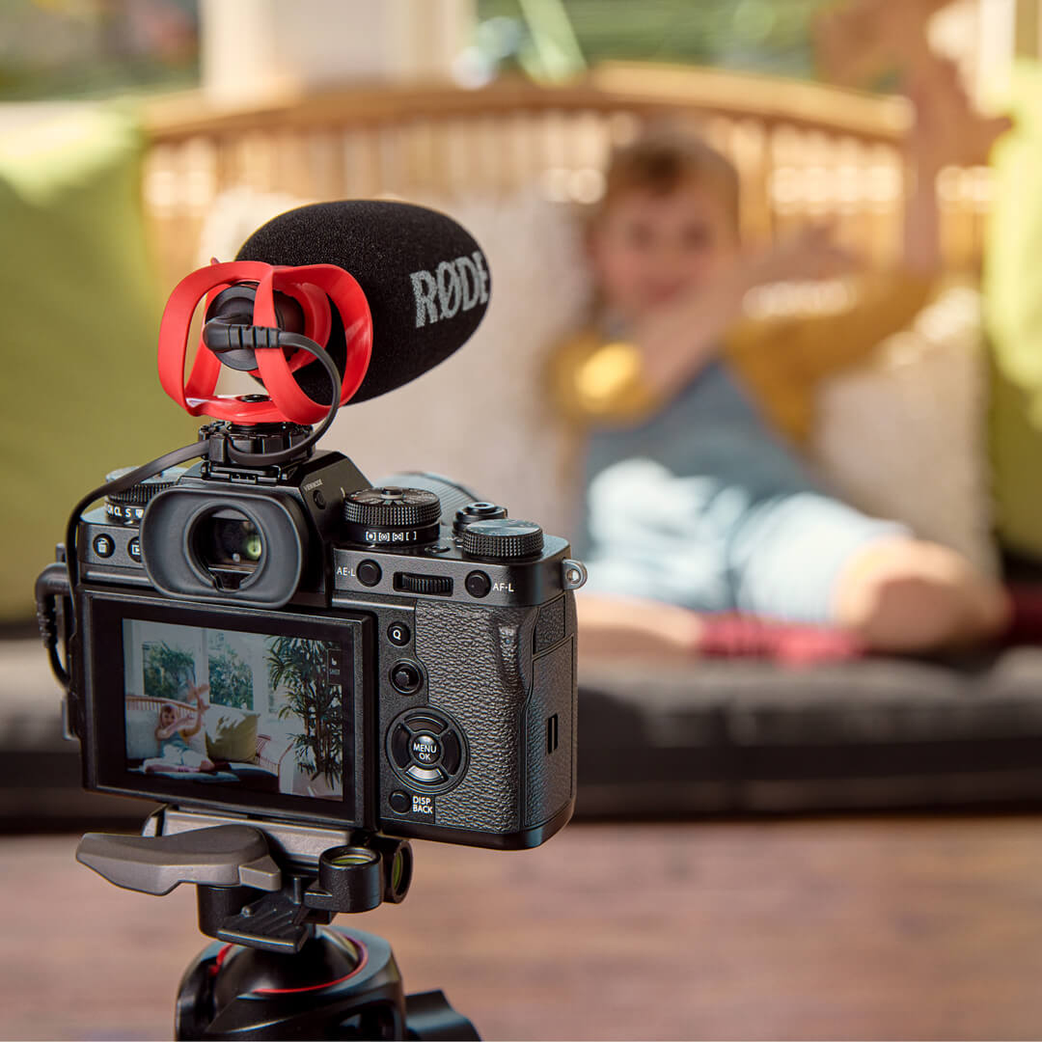 Camera with microphone films child on sofa in background.