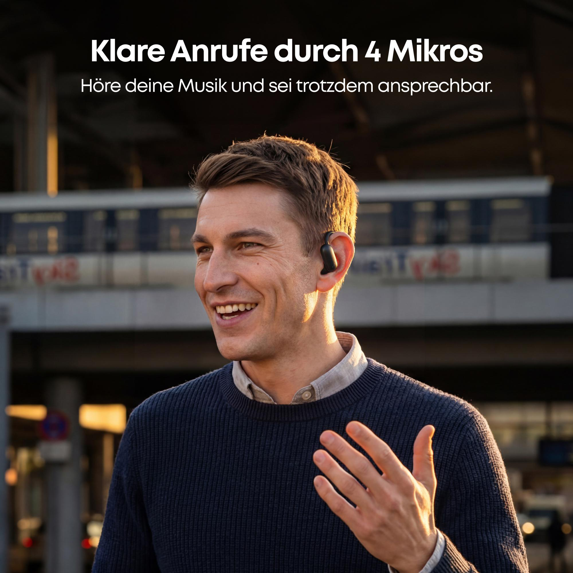 Ein Mann mit Kopfhörern lächelt, im Hintergrund ein Zug.