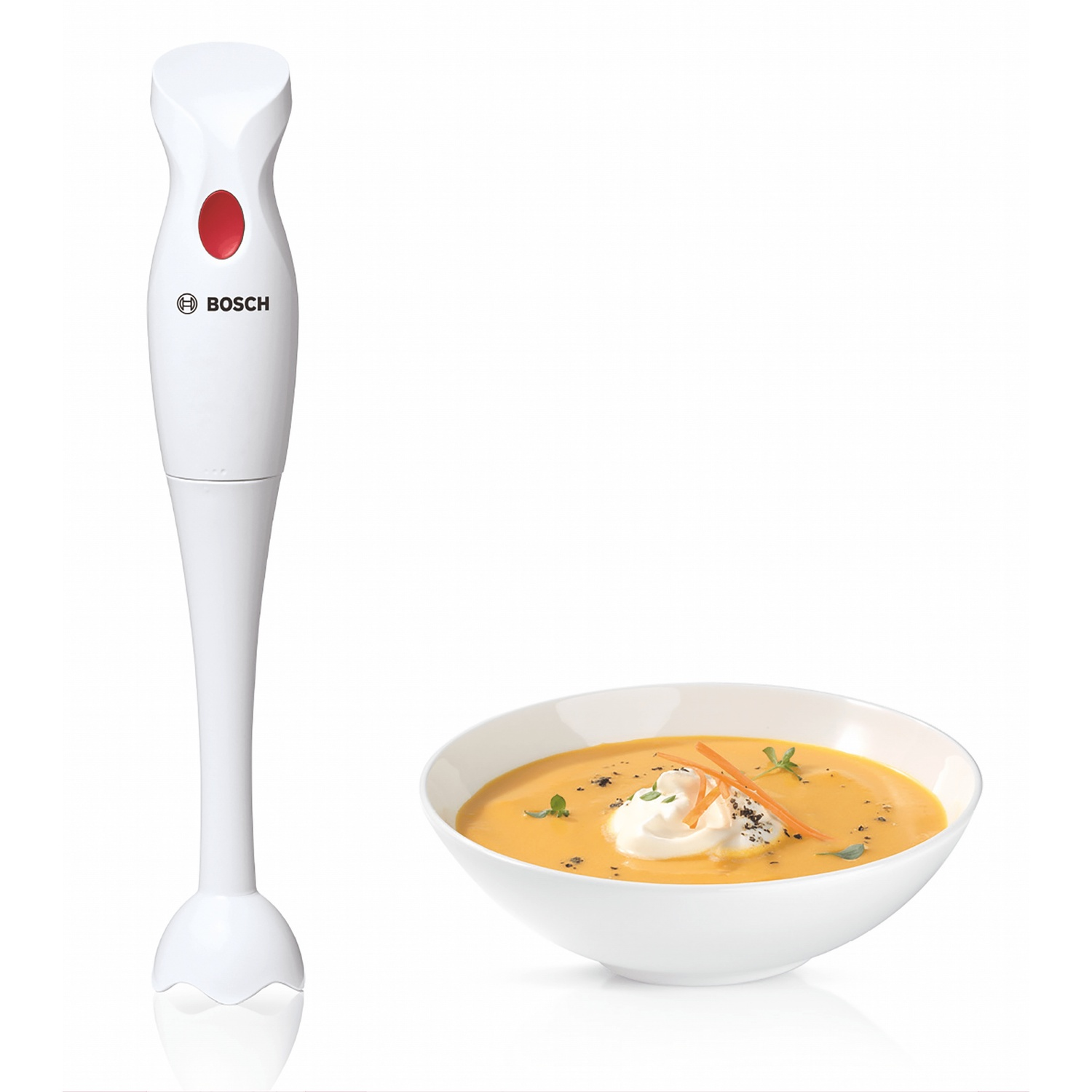 Un frullatore a immersione Bosch bianco accanto a una ciotola di vellutata di carote.