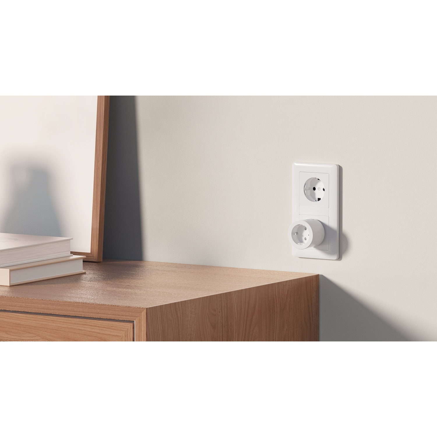 Un adattatore di presa bianco è inserito in una presa a muro sopra un mobile in legno.