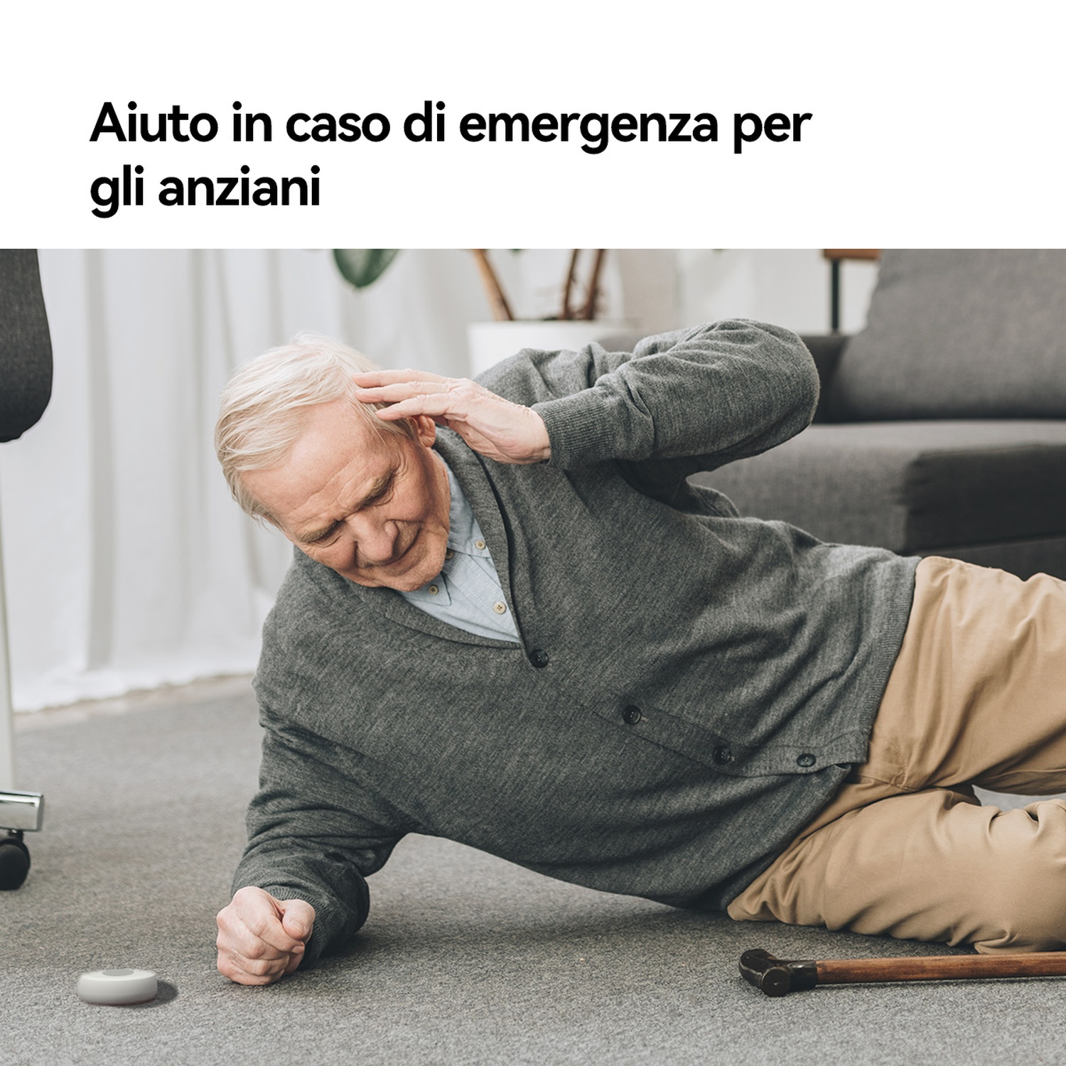 Un anziano in abiti grigi giace a terra, con una mano sulla testa.