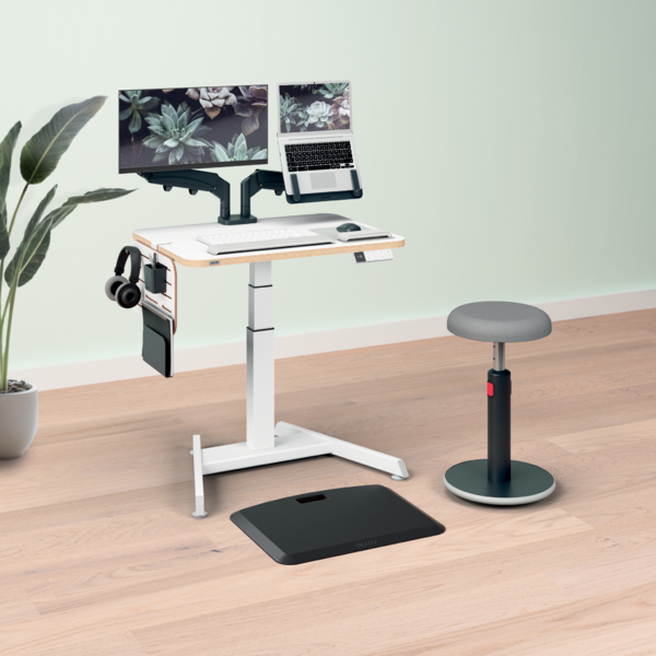 Ein höhenverstellbarer Schreibtisch mit zwei Monitoren, Laptop, Tastatur und Maus.