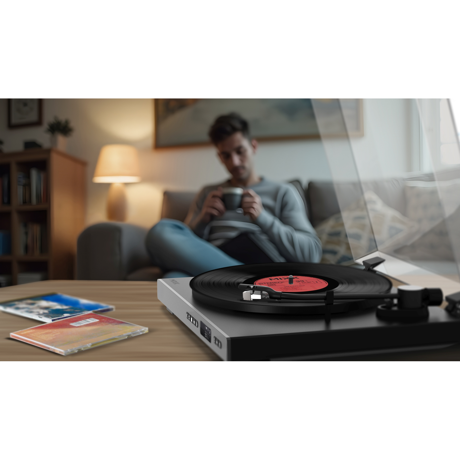 Man drinkt koffie terwijl plaat draait. Cd's liggen ernaast.