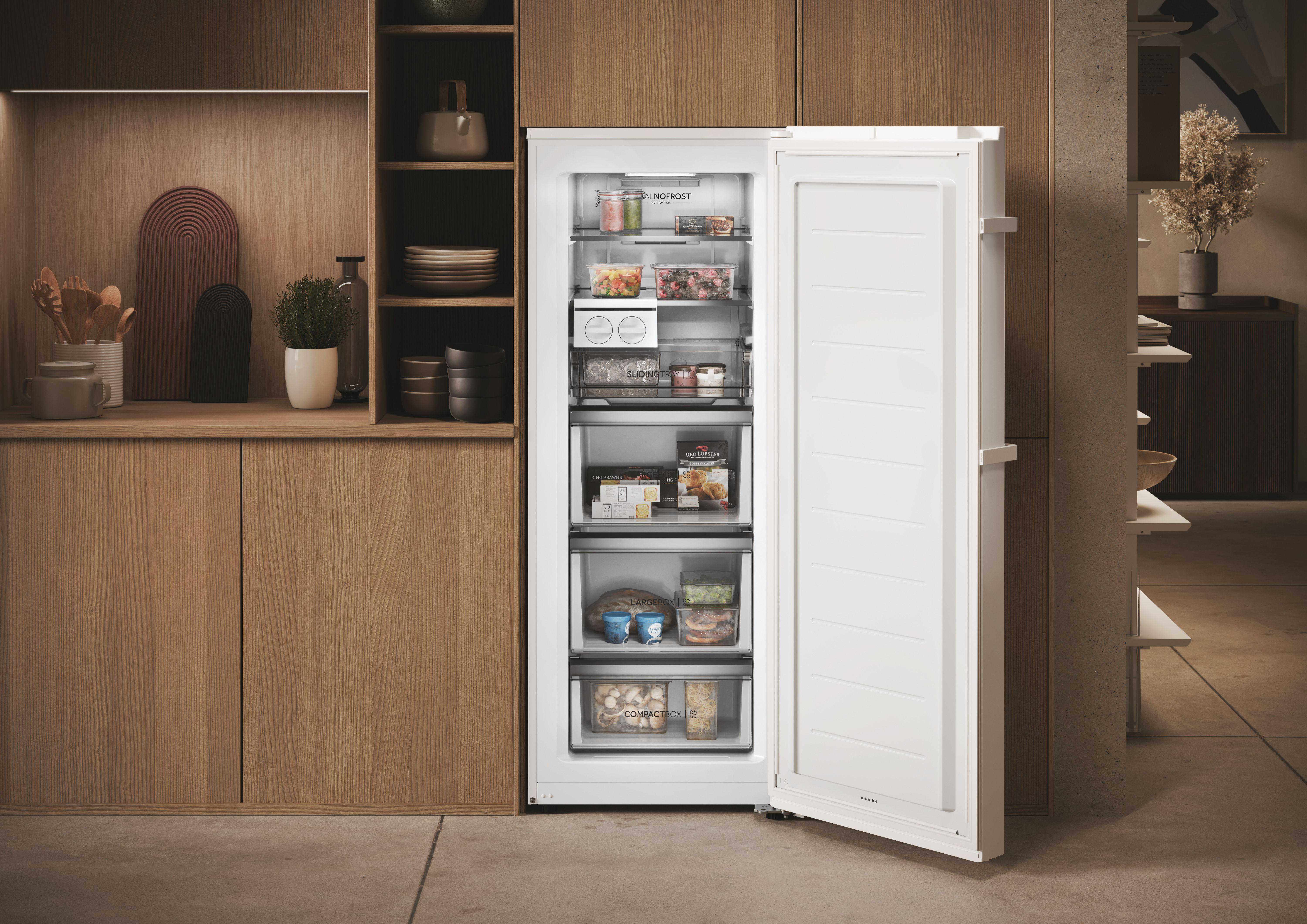 Offener weißer Kühlschrank mit Lebensmitteln und Holzschränken daneben.