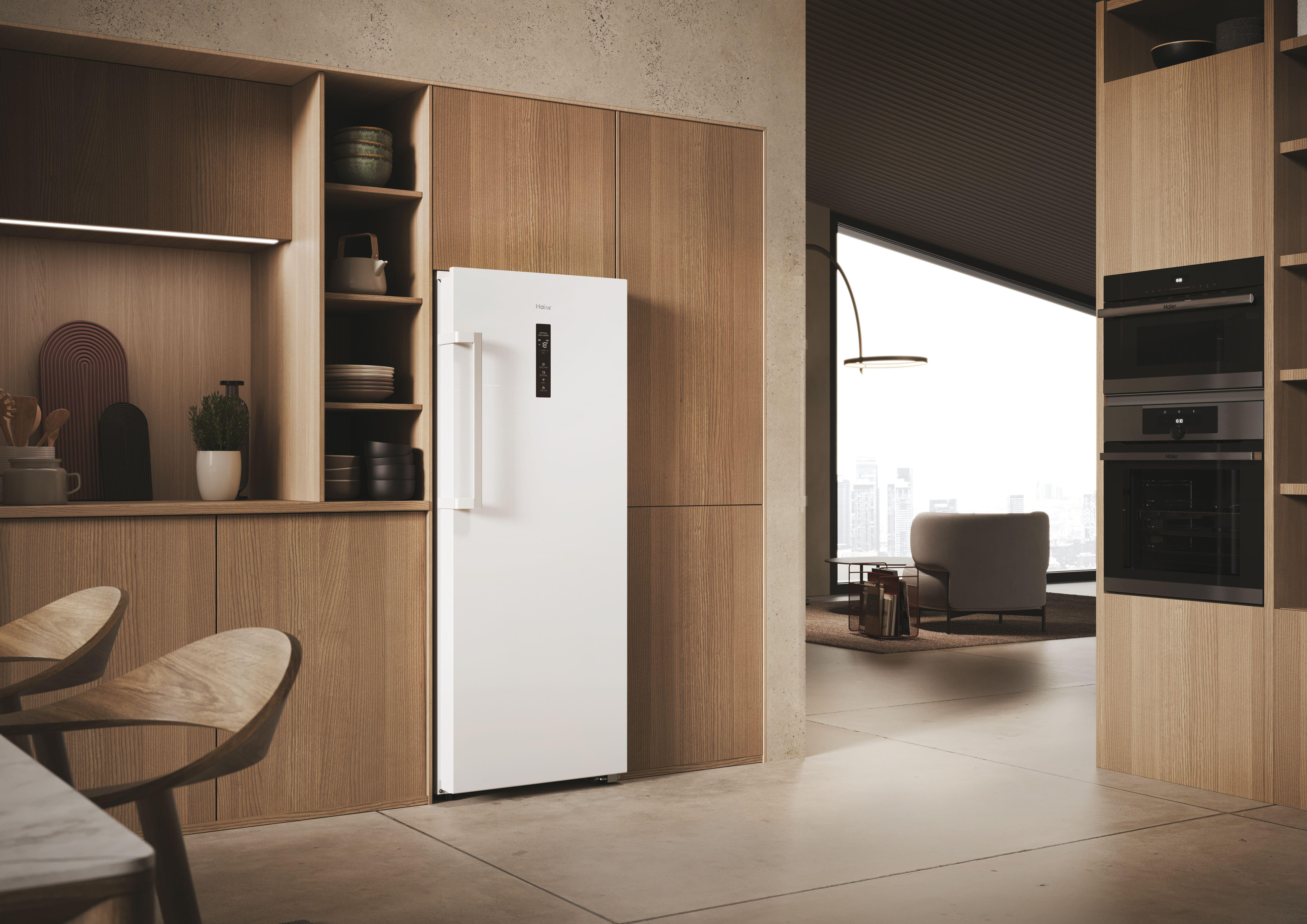Ein weißer Kühlschrank steht neben Holzschränken in einer modernen Küche mit Blick auf die Stadt.