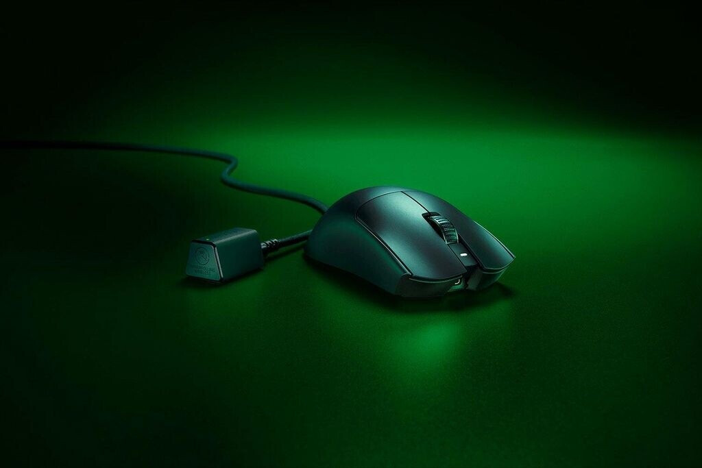 Fekete gamer egér kábellel és dongle-lal zöld háttéren.
