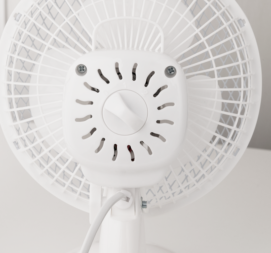 Zbliżenie białego tyłu wentylatora z otworami wentylacyjnymi i pokrętłem sterującym.