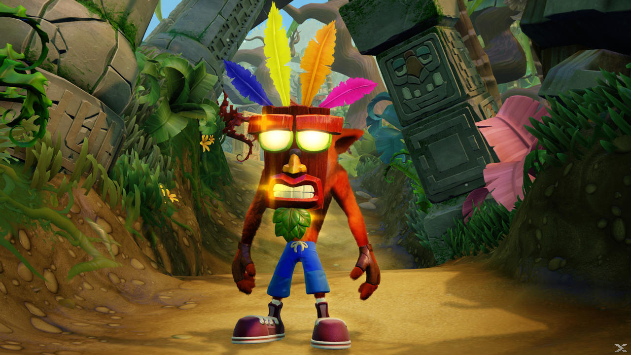 Crash Bandicoot stoi na ścieżce w dżungli, ma kolorowe pióra na głowie.