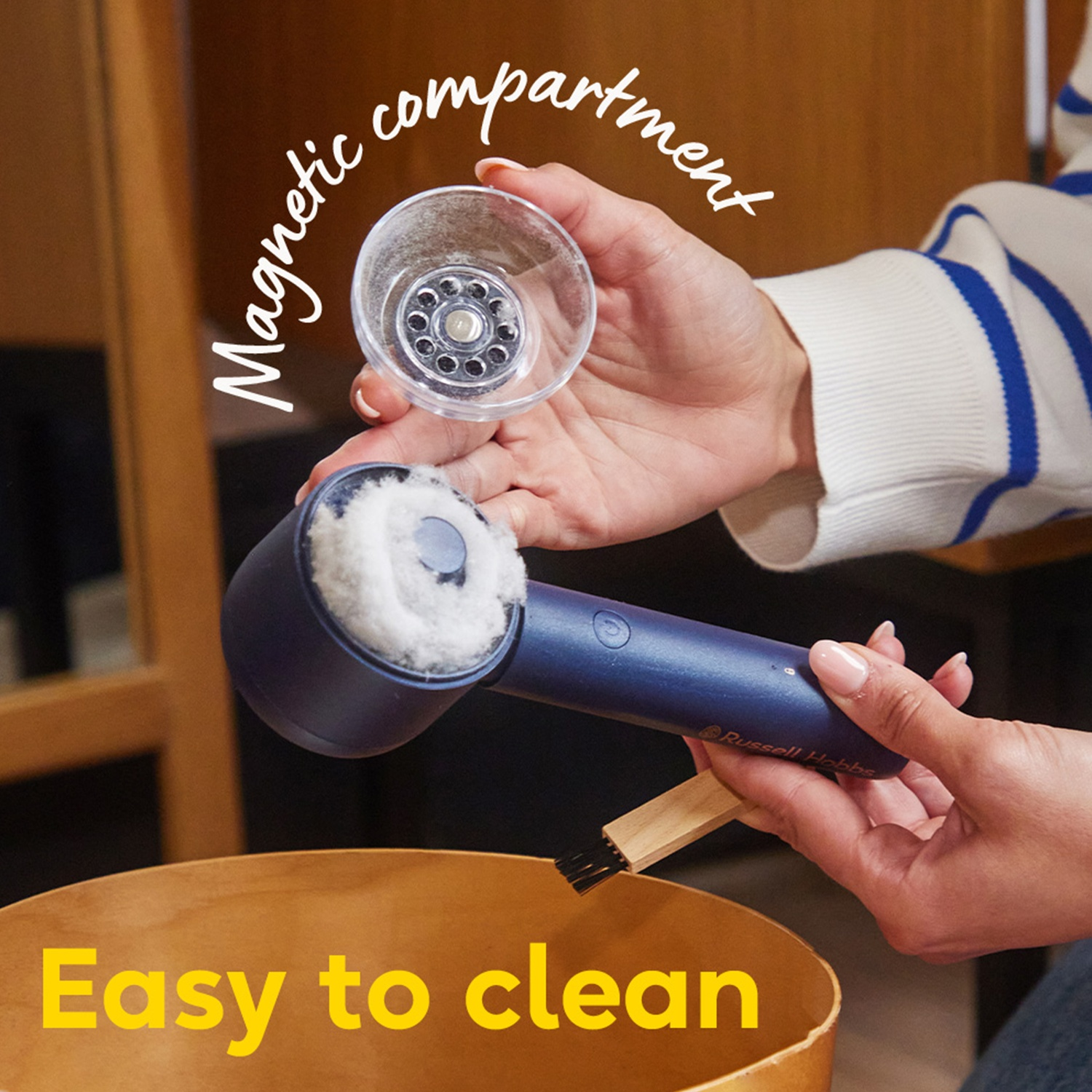 Une personne nettoie un aspirateur bleu portable. Compartiment magnétique et brosse montrés.