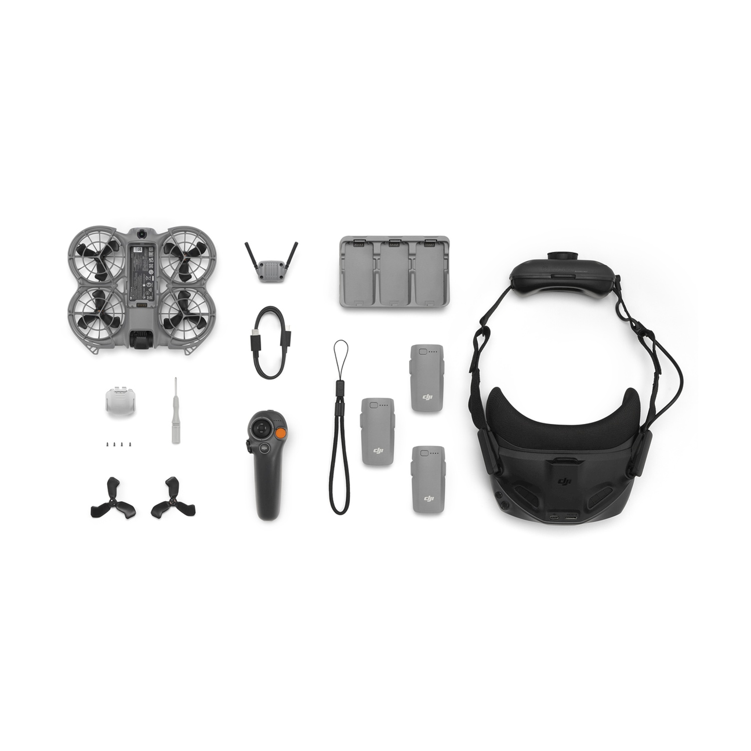 Drone, controller, occhiali e accessori disposti su sfondo bianco.