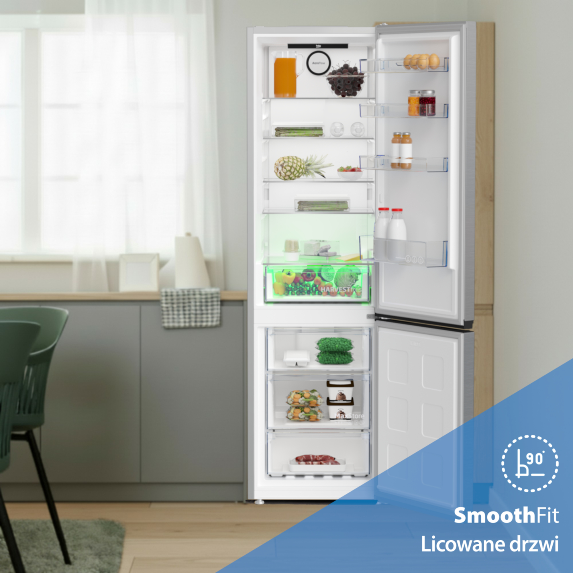 Otwarta lodówka wypełniona jedzeniem i szufladami. Z przodu zielone krzesła.