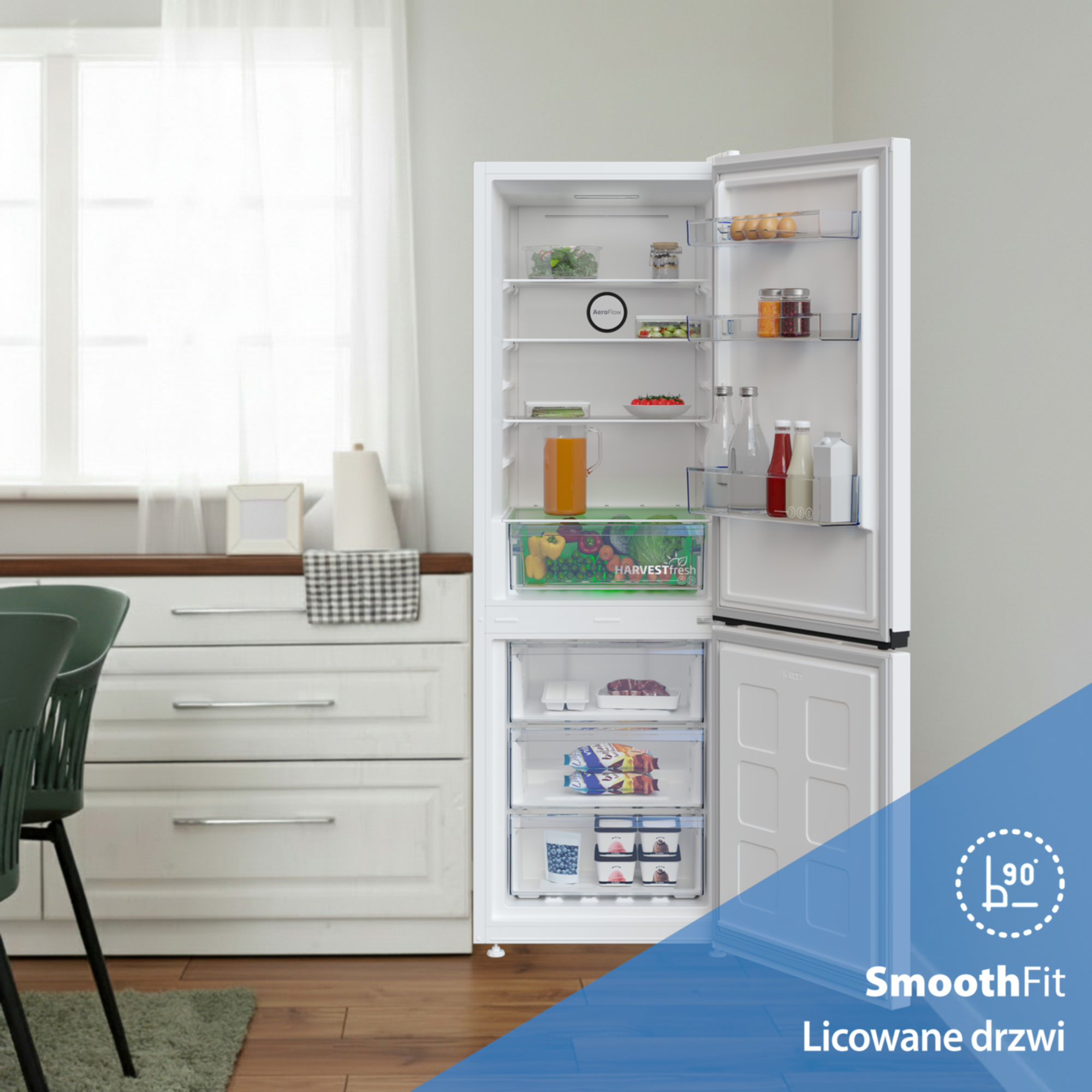 Otwarta lodówka z jedzeniem i szufladami. Obok biała komoda.