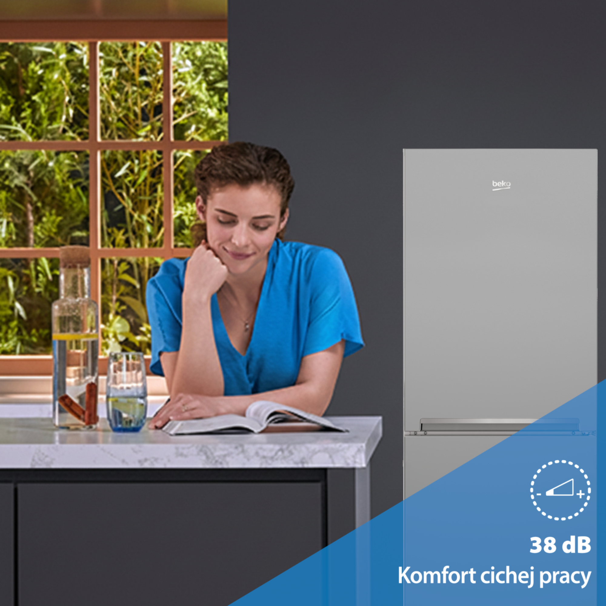 Kobieta czyta przy stole obok lodówki. Poziom hałasu 38 dB.