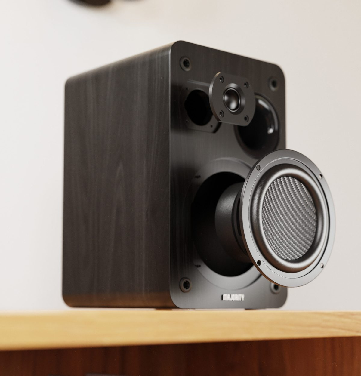 Un altoparlante nero con il woofer esposto, su una superficie di legno.