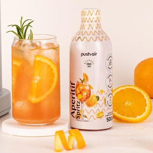 Szklanka Aperitif Spritz z pomarańczą i rozmarynem obok butelki.